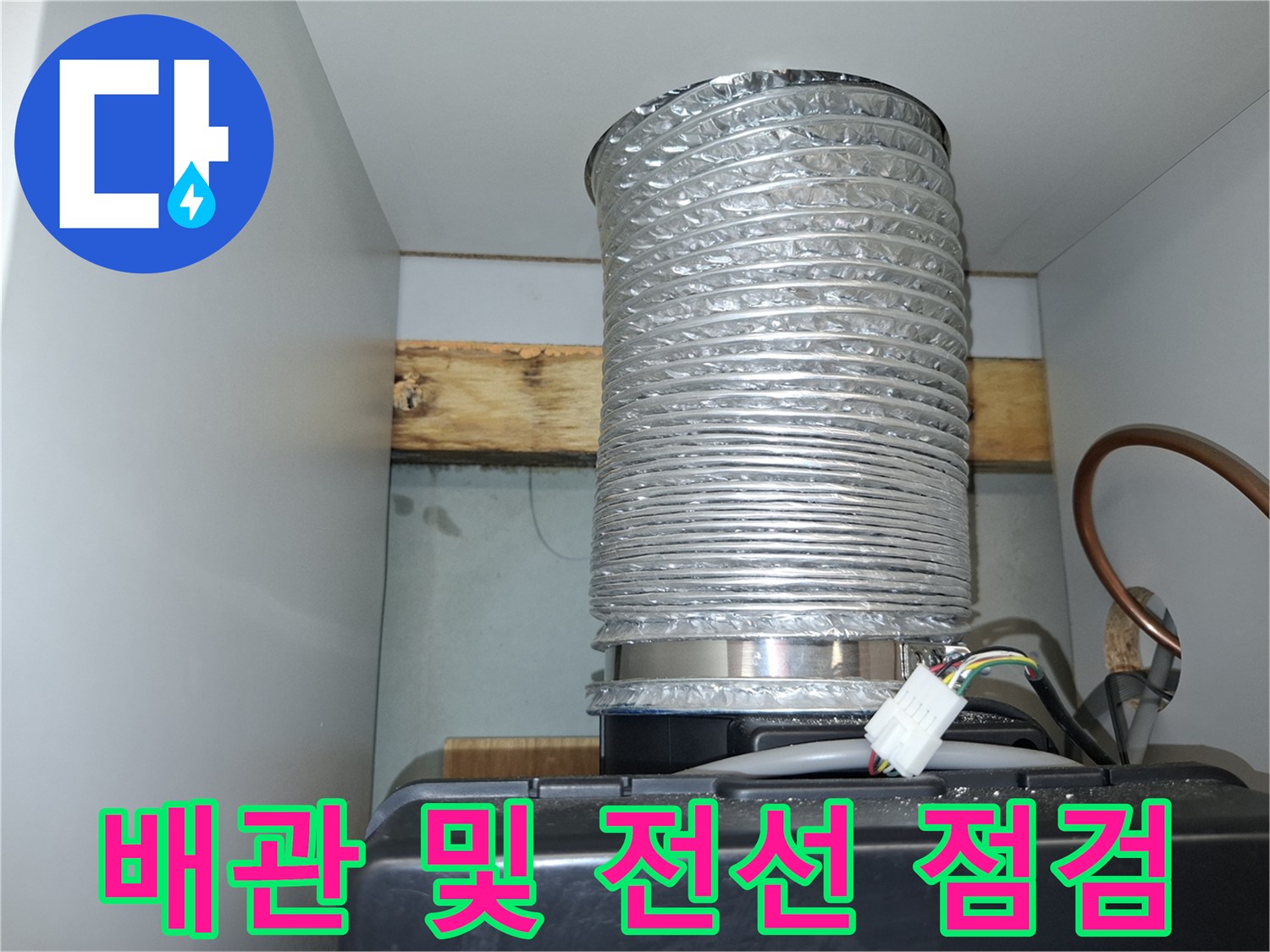 주방 상부장 내부의 은색 배수 호스와 전기 커넥터 모습