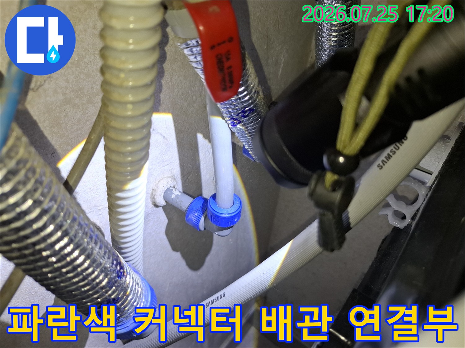 삼성 로고가 적힌 흰색 배관과 파란색 플라스틱 커넥터가 연결된 모습