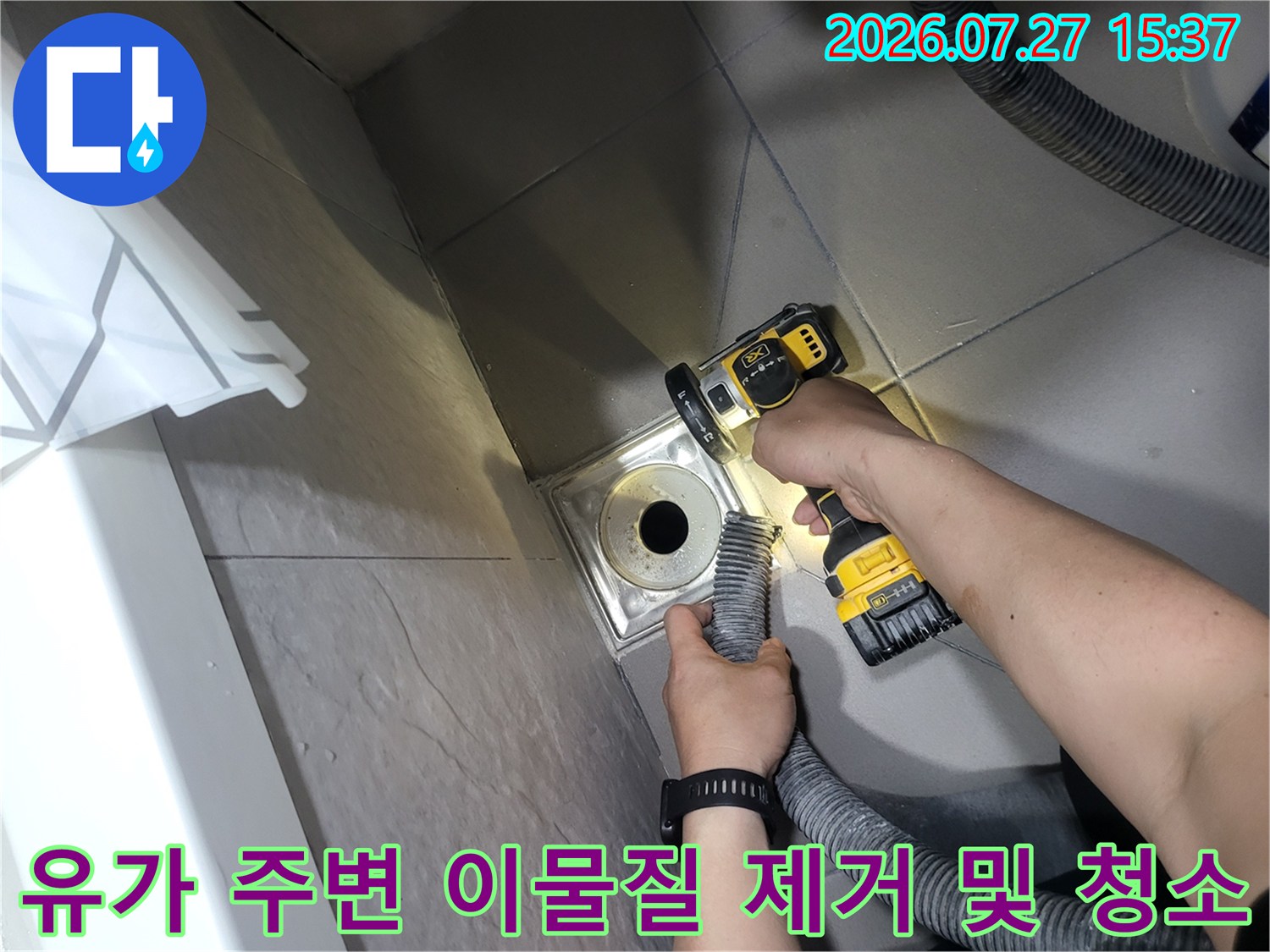 밝은 조명 아래에서 전동 브러시로 화장실 배수구 유가의 틈새를 세척하는 작업 모습
