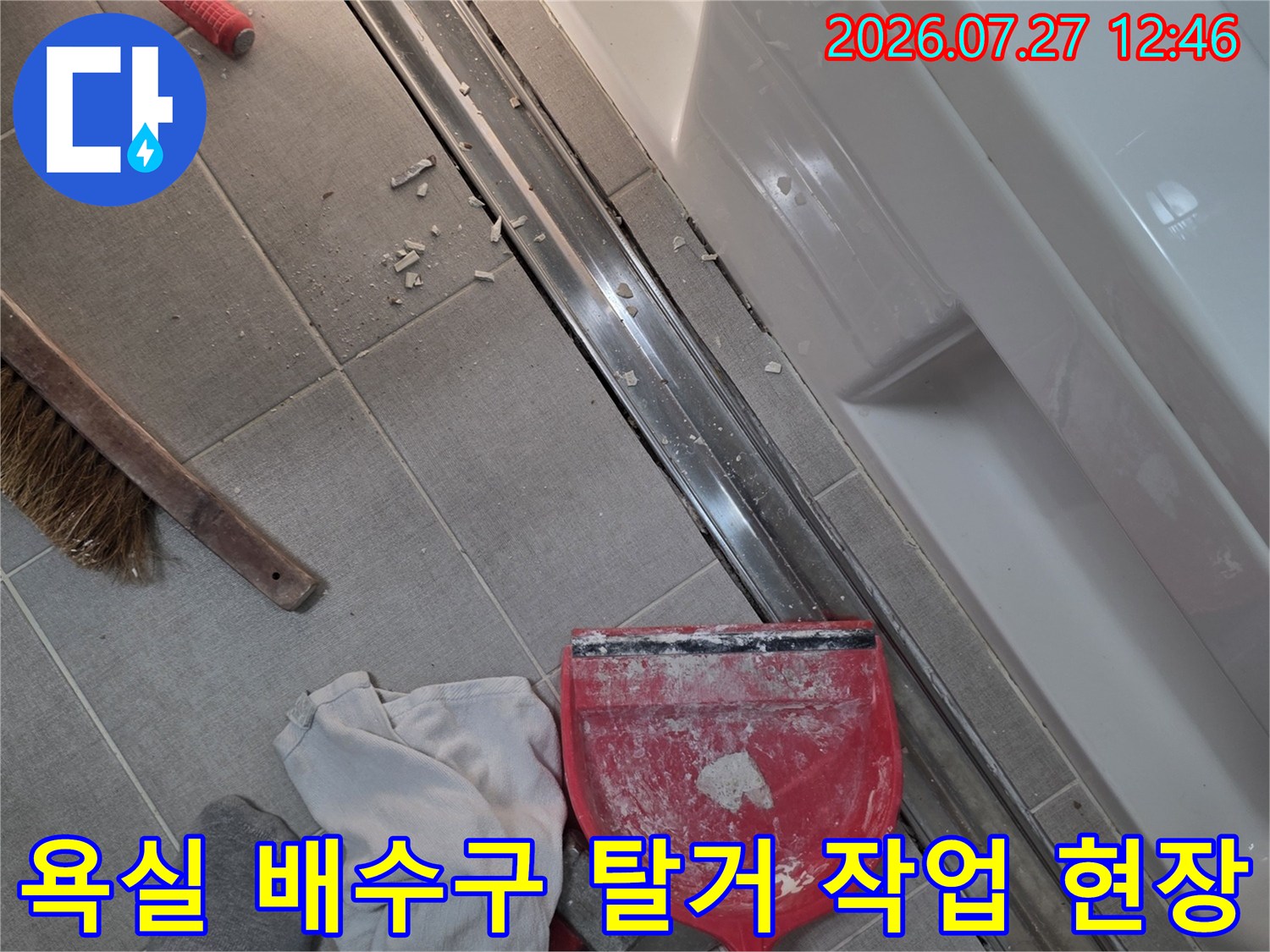 탈거된 긴 금속 트랜치와 그 옆에 놓인 빨간색 쓰레받기와 수건