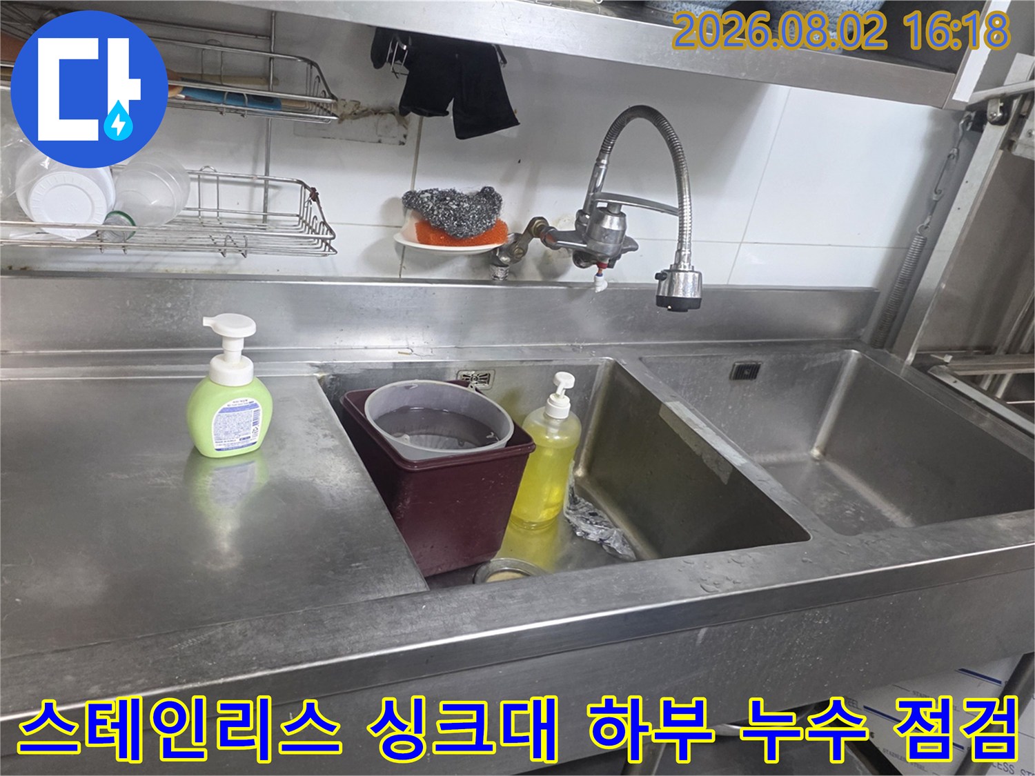 금속 재질의 대형 싱크대 내부에 위치한 수전과 배관 시설