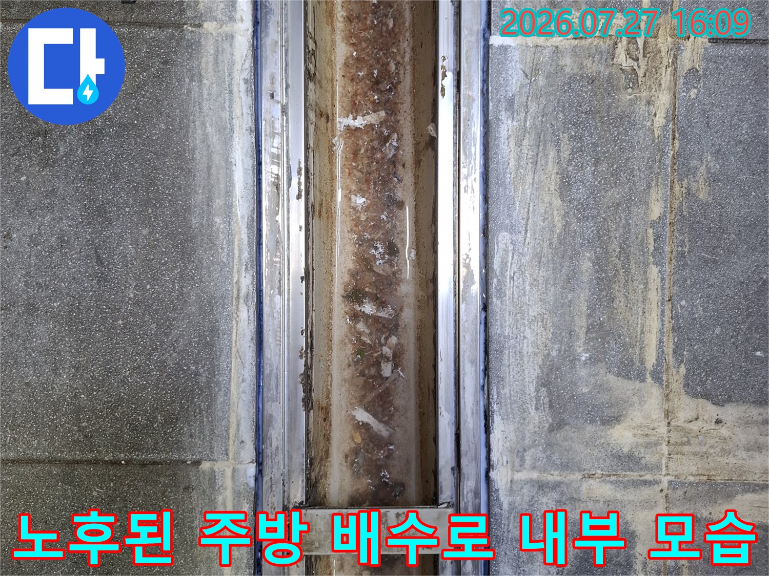 스테인리스 소재의 주방 배수로 내부에 누적된 찌꺼기와 주변 타일 마감재의 노후 상태-사진