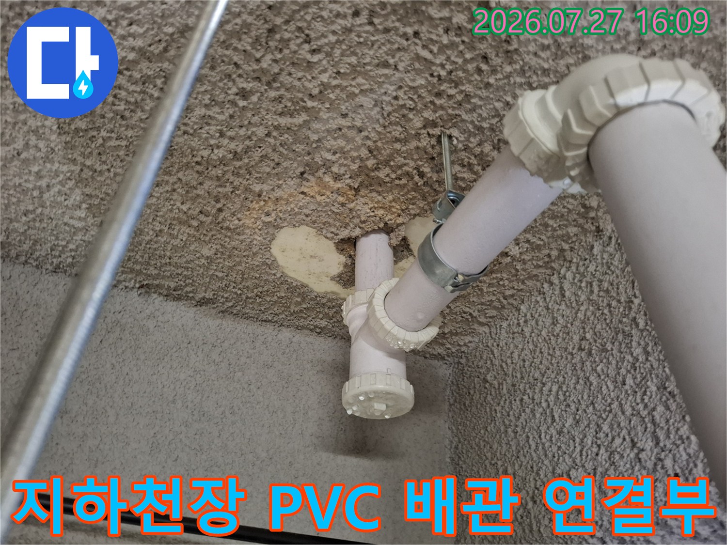 콘크리트 천장에 설치된 흰색 PVC 배관과 연결 부속-금속 고정 밴드로 고정된 모습