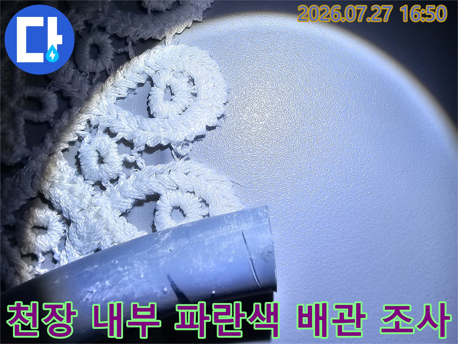 강한 조명으로 비추어진 화장실 천장의 파란색 플라스틱 배관과 주변의 흰색 구조물