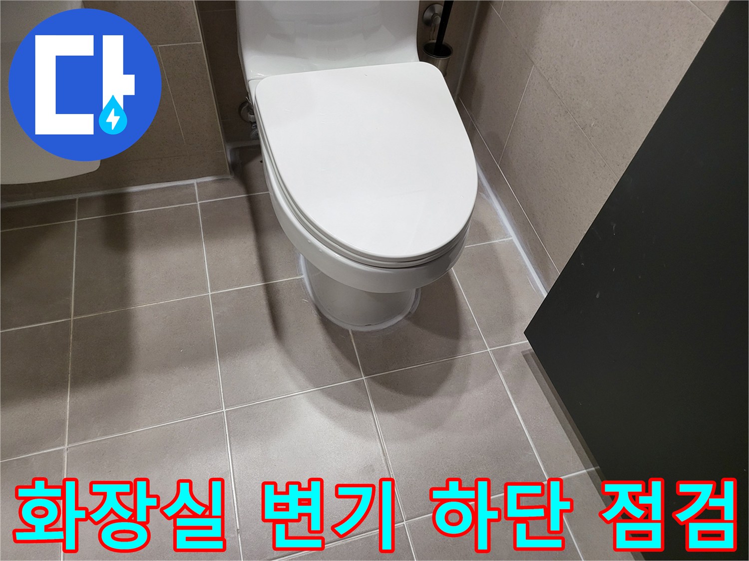변기 아래쪽 타일 마감과 배관 연결 부위의 근접 촬영