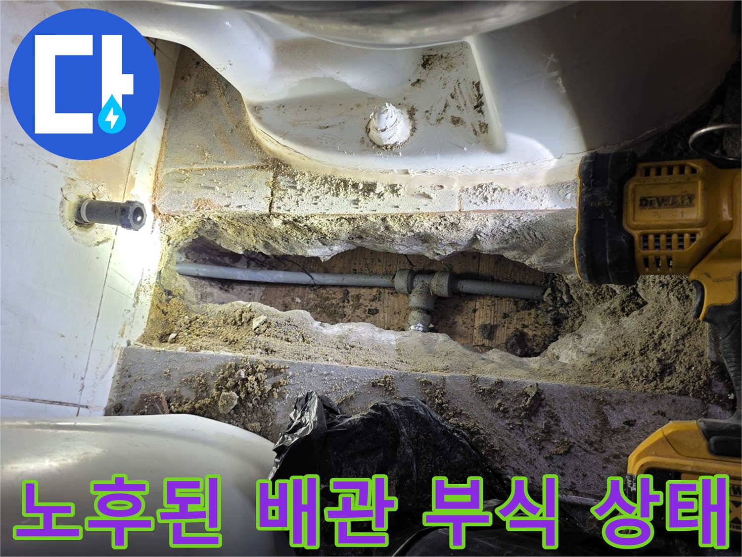 변기 주변 바닥 아래 노출된 파손된 금속 배관과 젖은 흙