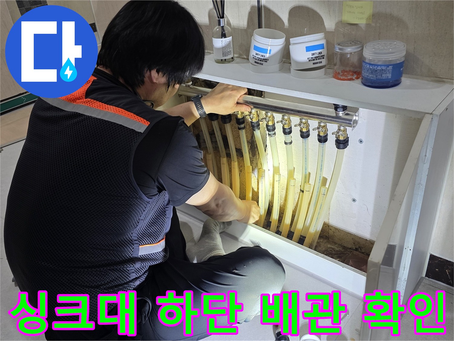 싱크대 아래쪽 밸브와 여러 갈래의 수도 관로를 점검하는 모습