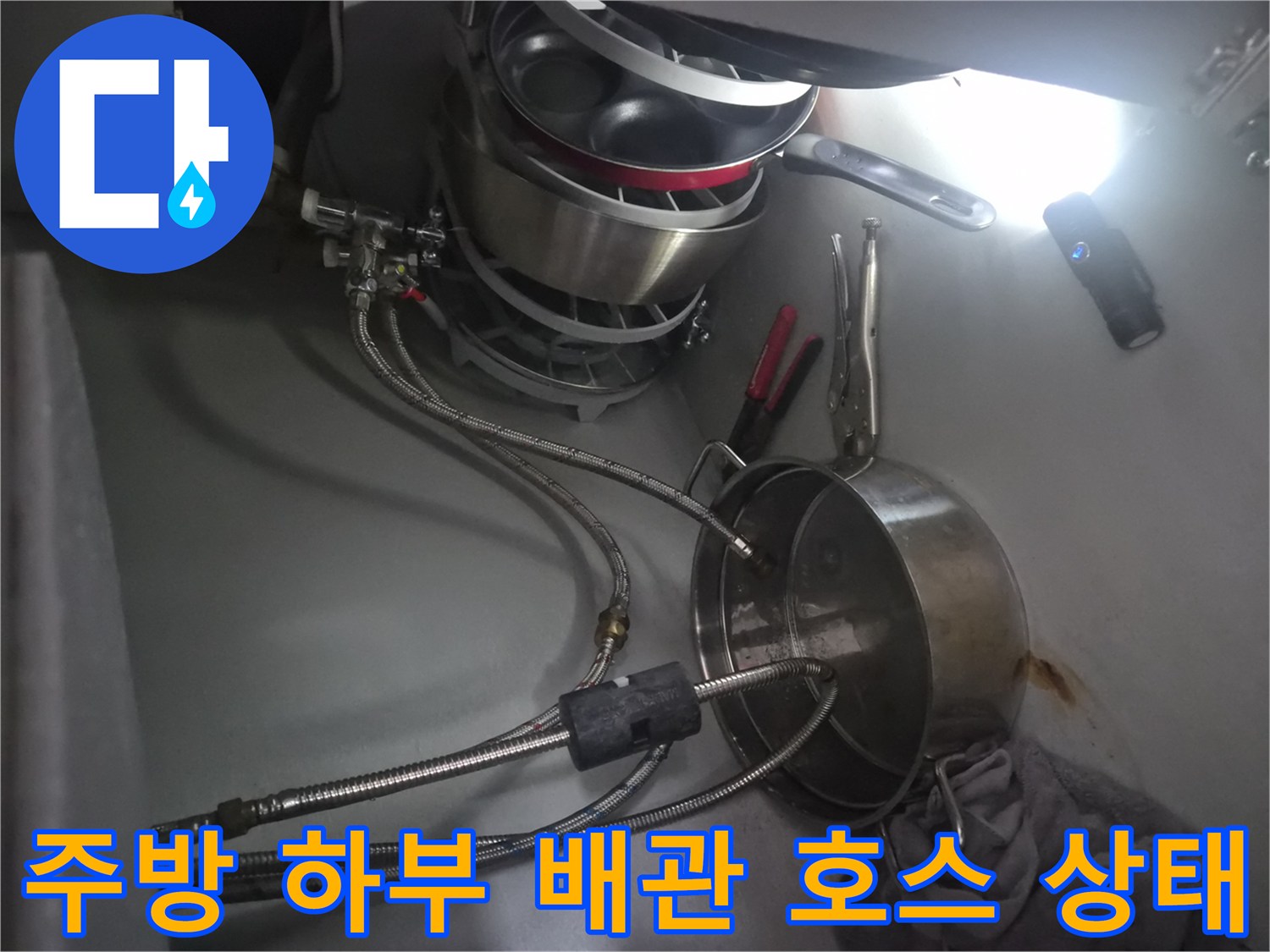 싱크대 밑 냄비와 함께 놓인 식기세척기 급수용 플렉시블 호스