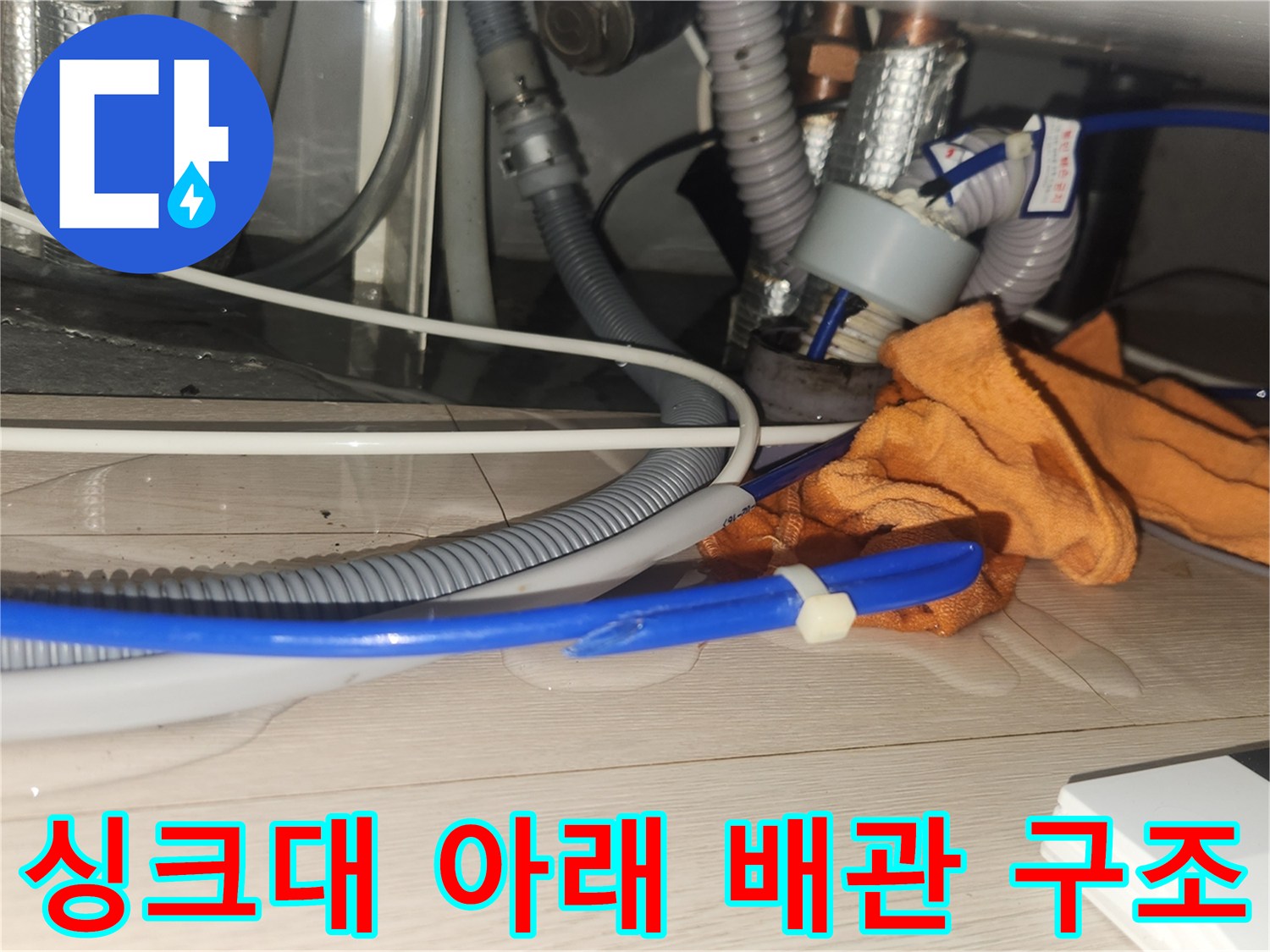 작업용 장갑과 함께 보이는 싱크대 하단 배관의 복잡한 구조