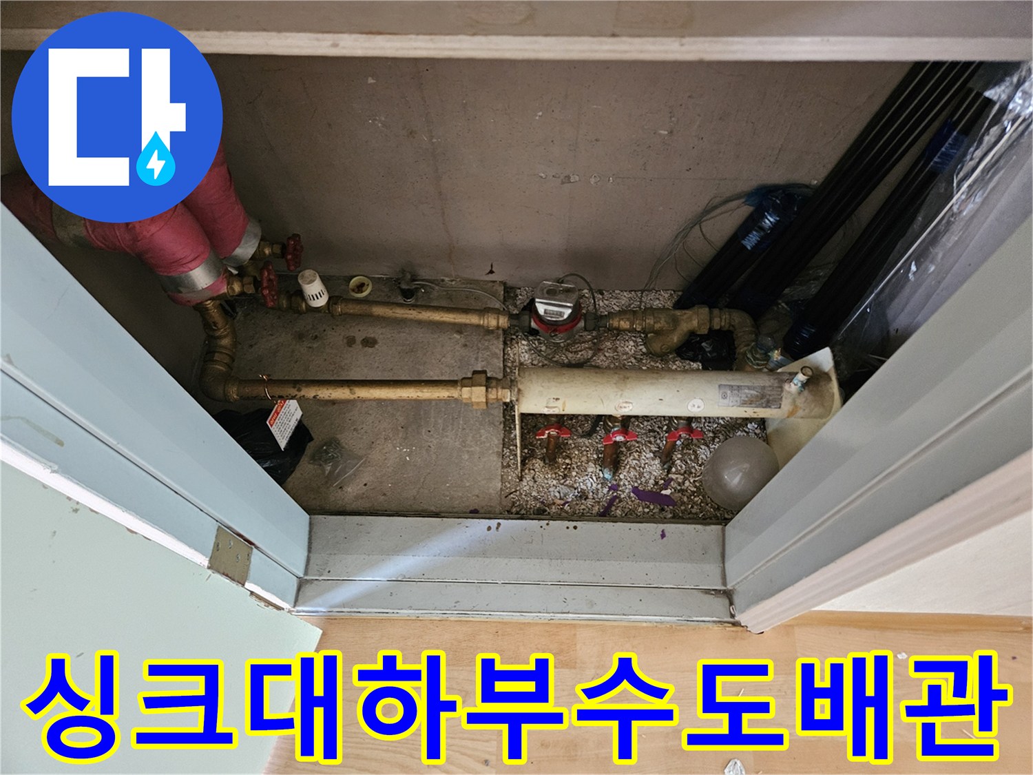 주방 싱크대 밑 공간의 금속 배관과 제어 밸브 모습