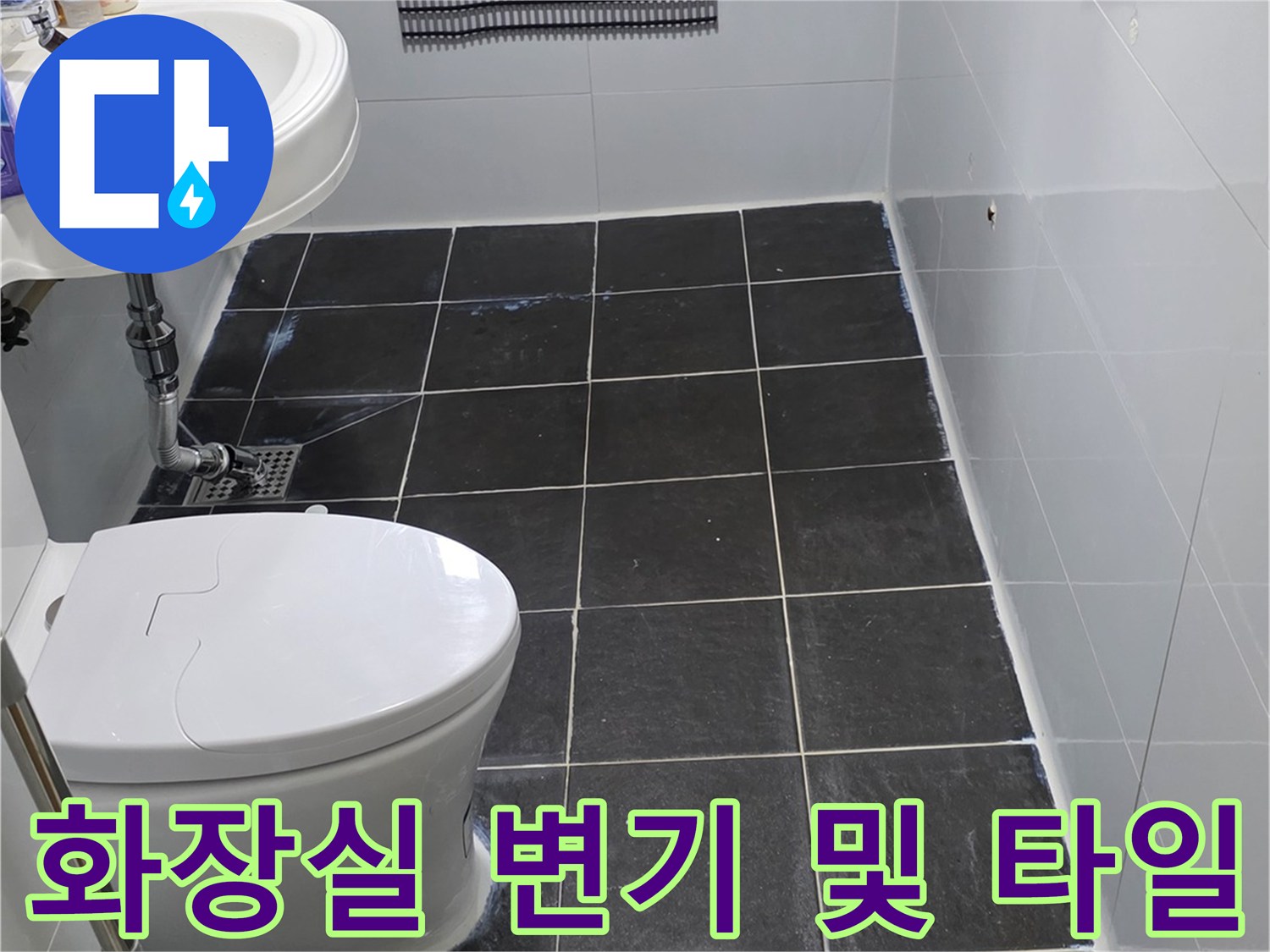 변기 뒤쪽 벽면의 어두운 색상 타일과 설치된 양변기 이미지