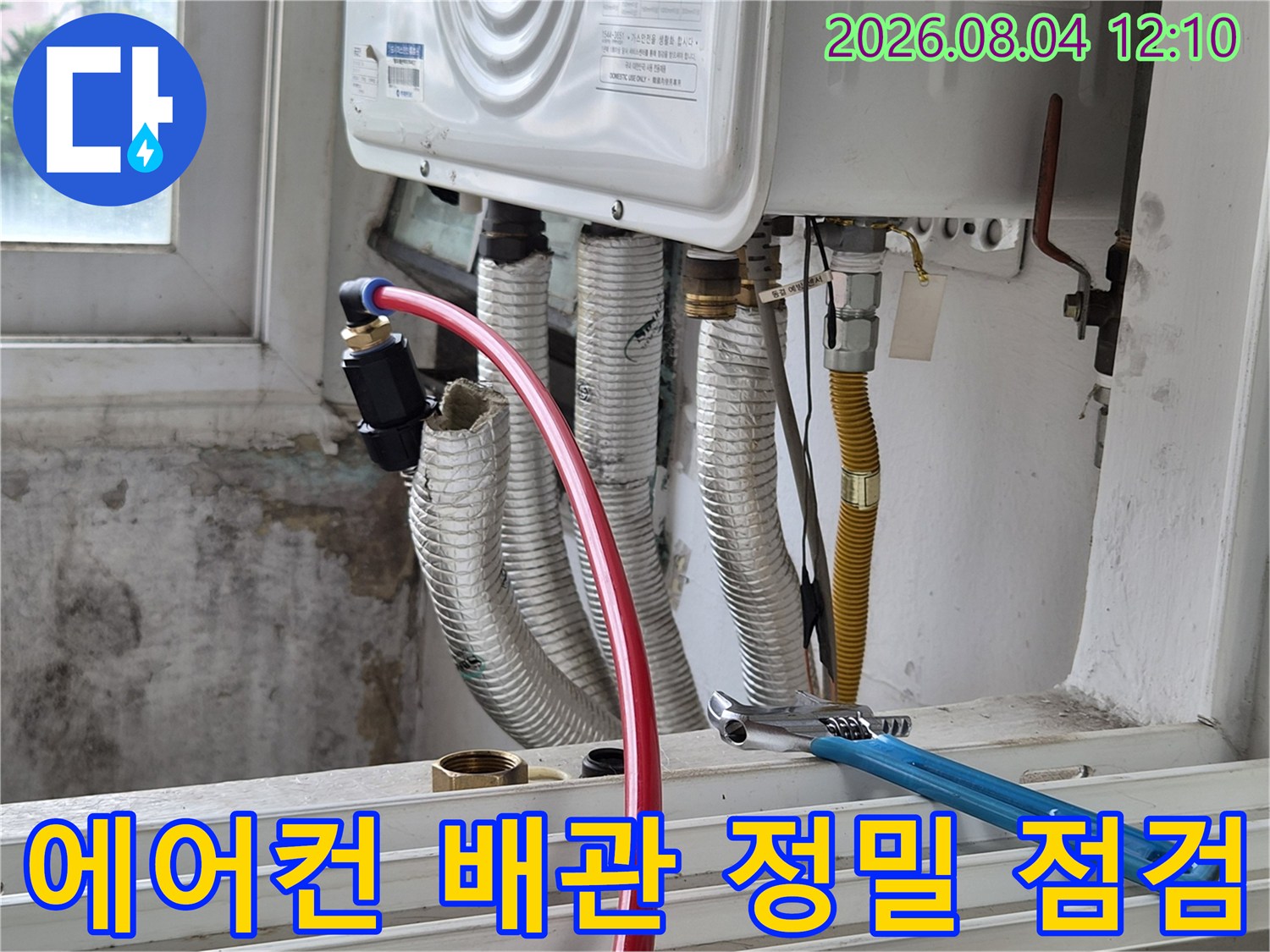 에어컨 실내기 하부 노출된 여러 개의 보온재 감싼 배관과 몽키스패너 작업 도구