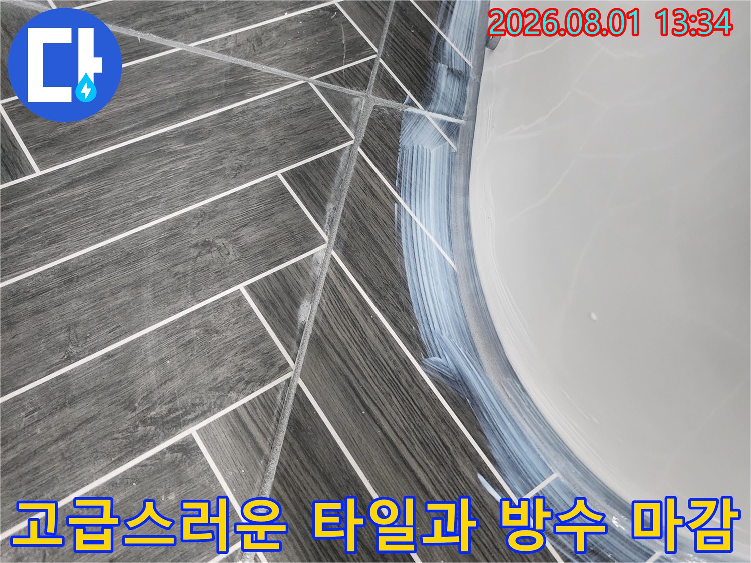 기하학적 문양의 그레이색 타일과 흰색 실리콘으로 경계를 구분한 욕실 바닥면