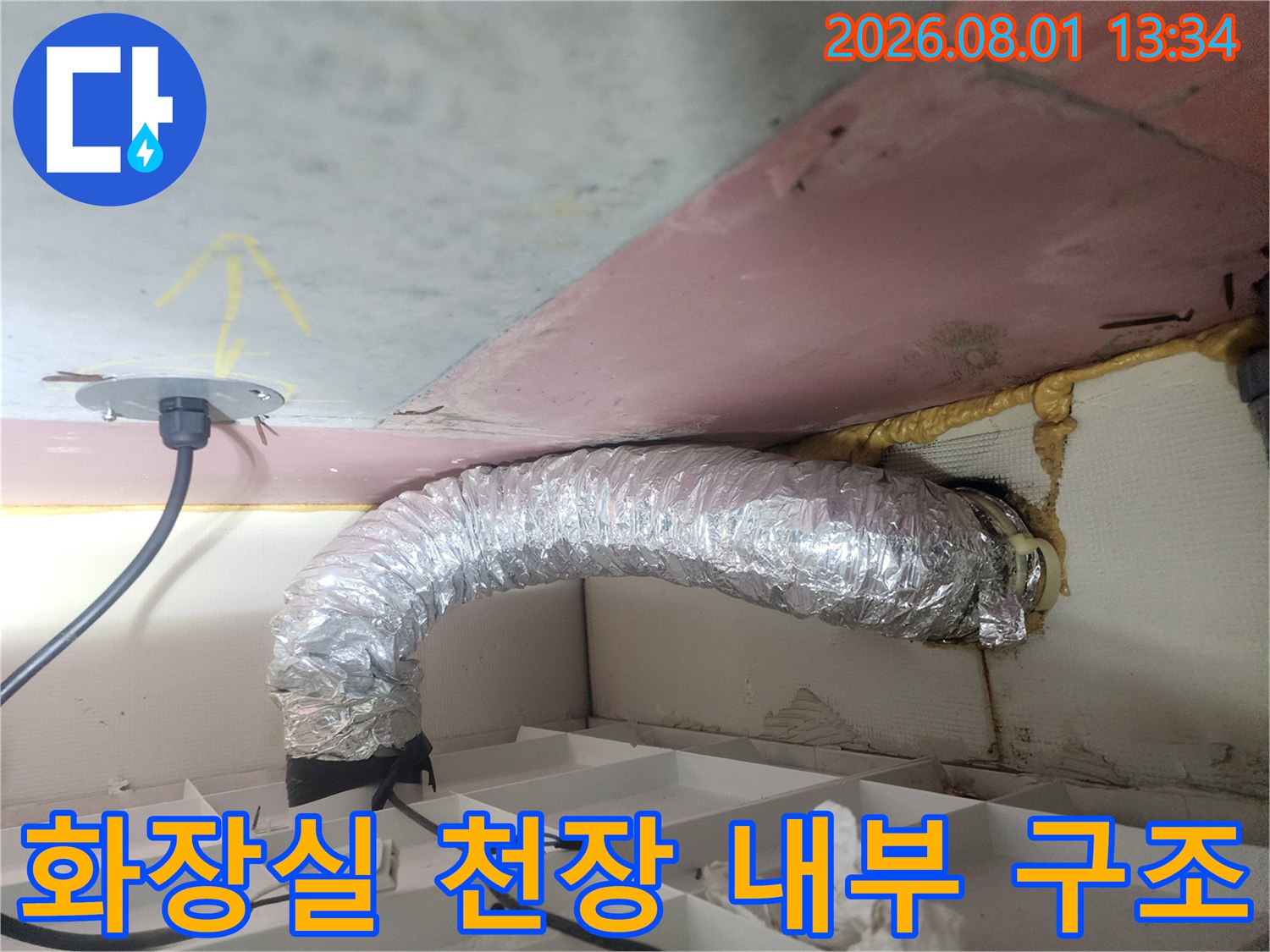 은색 단열재로 감싼 배관과 전선이 위치한 화장실 천장 내벽