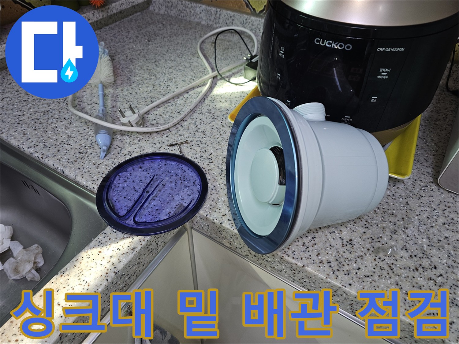 주방 싱크대 하부의 배관 덮개와 주변 환경을 촬영한 사진입니다.
