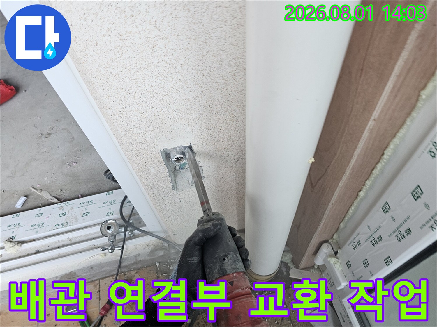 세탁실 벽면에 노출된 배관의 연결 부위를 확인하며 수리 작업을 진행하는 장면