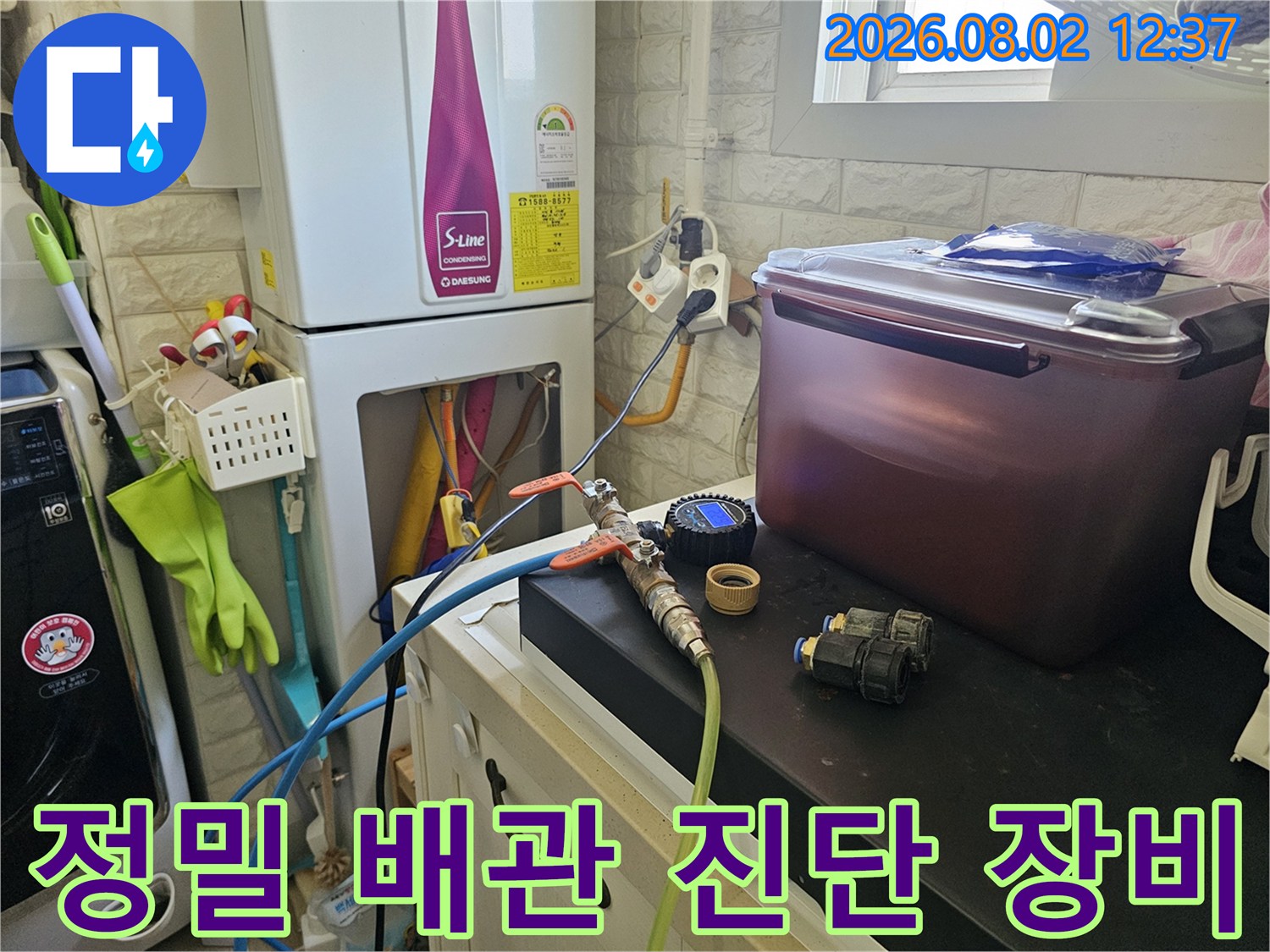 화장실 내 위치한 수도 배관에 청음 장비를 연결하여 누수 지점을 찾는 장면