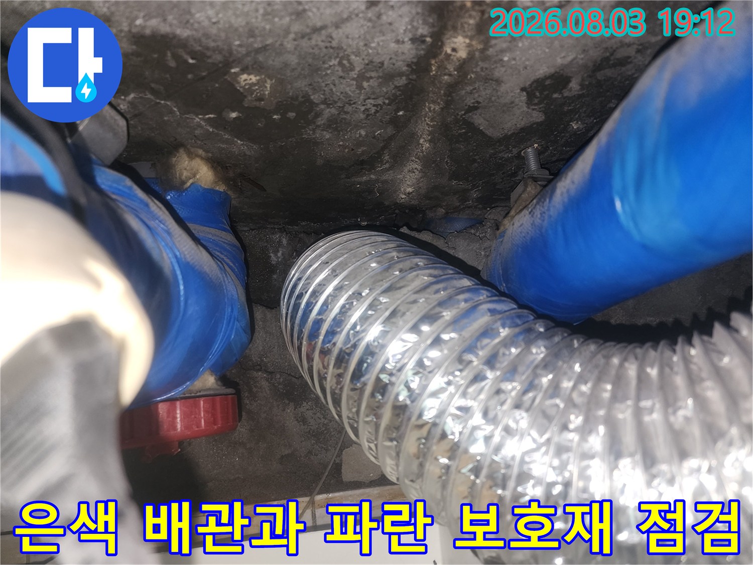 욕조 아래 설치된 은색 주름형 호스와 파란색 덮개로 감싸진 결합부