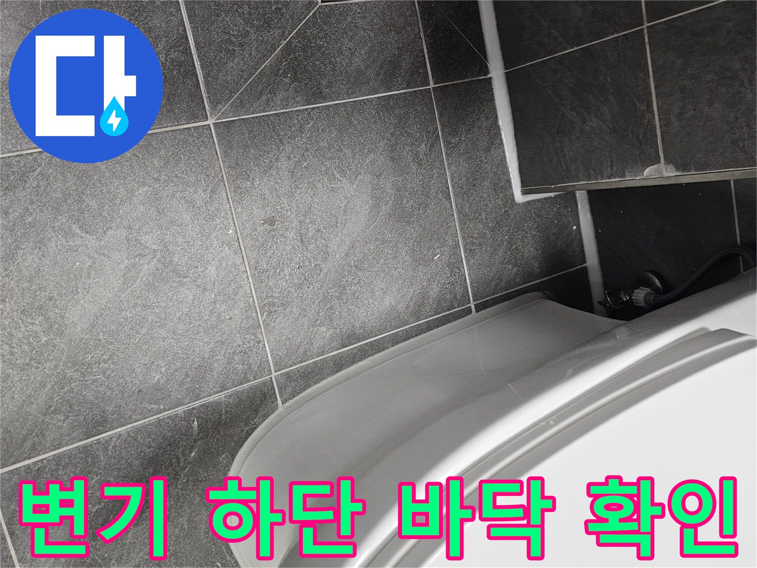 양변기 옆 타일 바닥과 검은색 배수구 유가 부분의 근접 촬영
