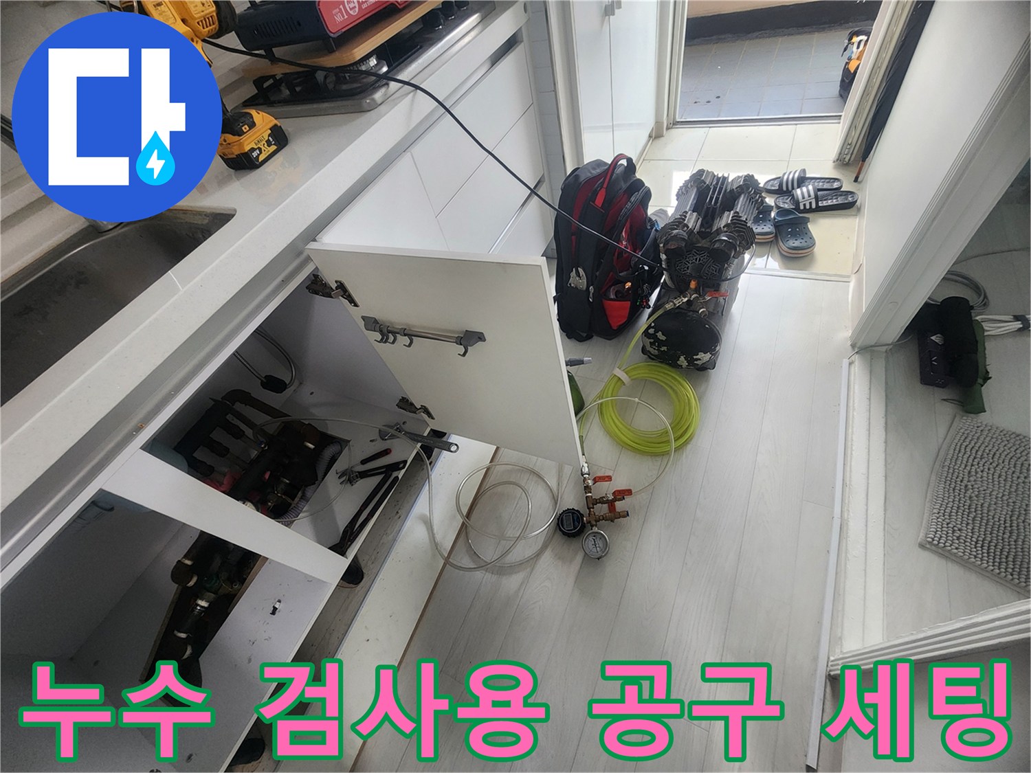 배관 압력 테스트를 위해 싱크대 하부에 배치된 호스와 전동 드릴