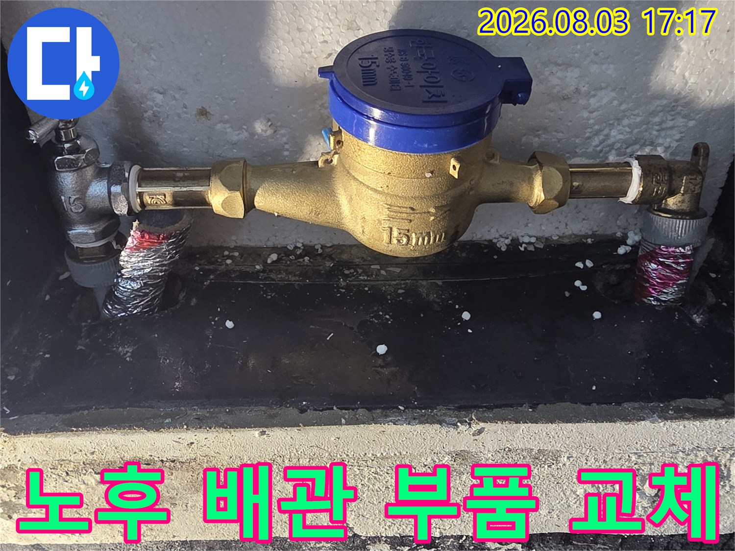 파란색 계량기와 금속 파이프가 연결된 수도 시설 모습