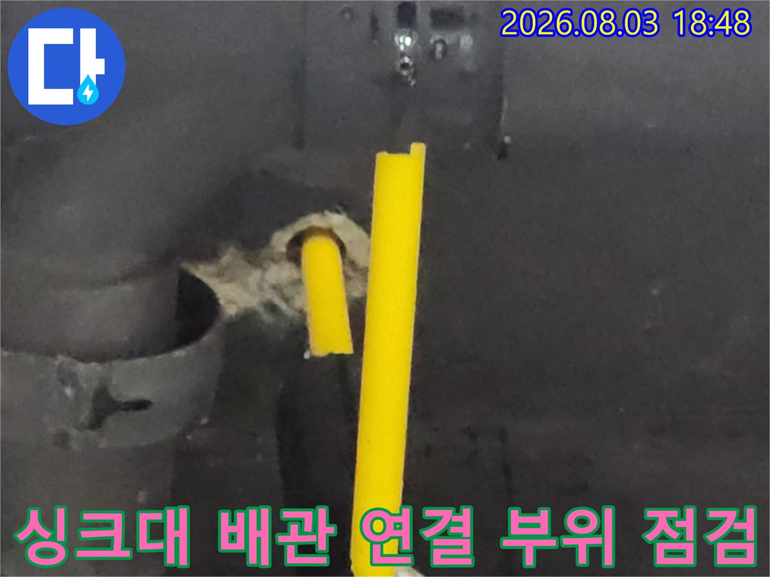 싱크대 아래 노란색 배관과 호스 연결부의 수밀성을 확인하는 작업 사진