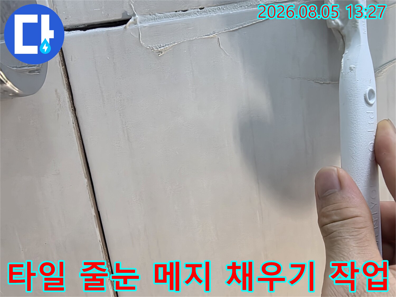 전문가용 도구를 사용하여 타일 사이 빈틈을 방수재로 채우는 상세 컷