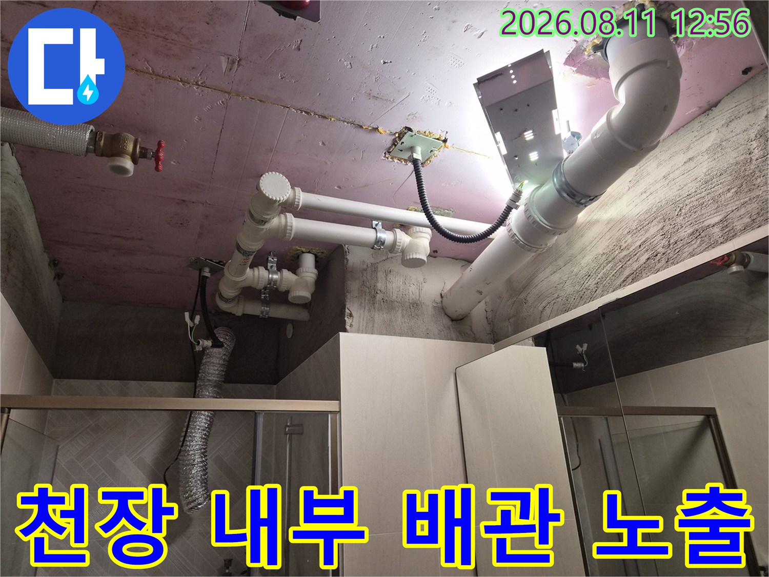 조명을 비추어 상세히 점검 중인 욕실 천장 하수 및 오수 배관