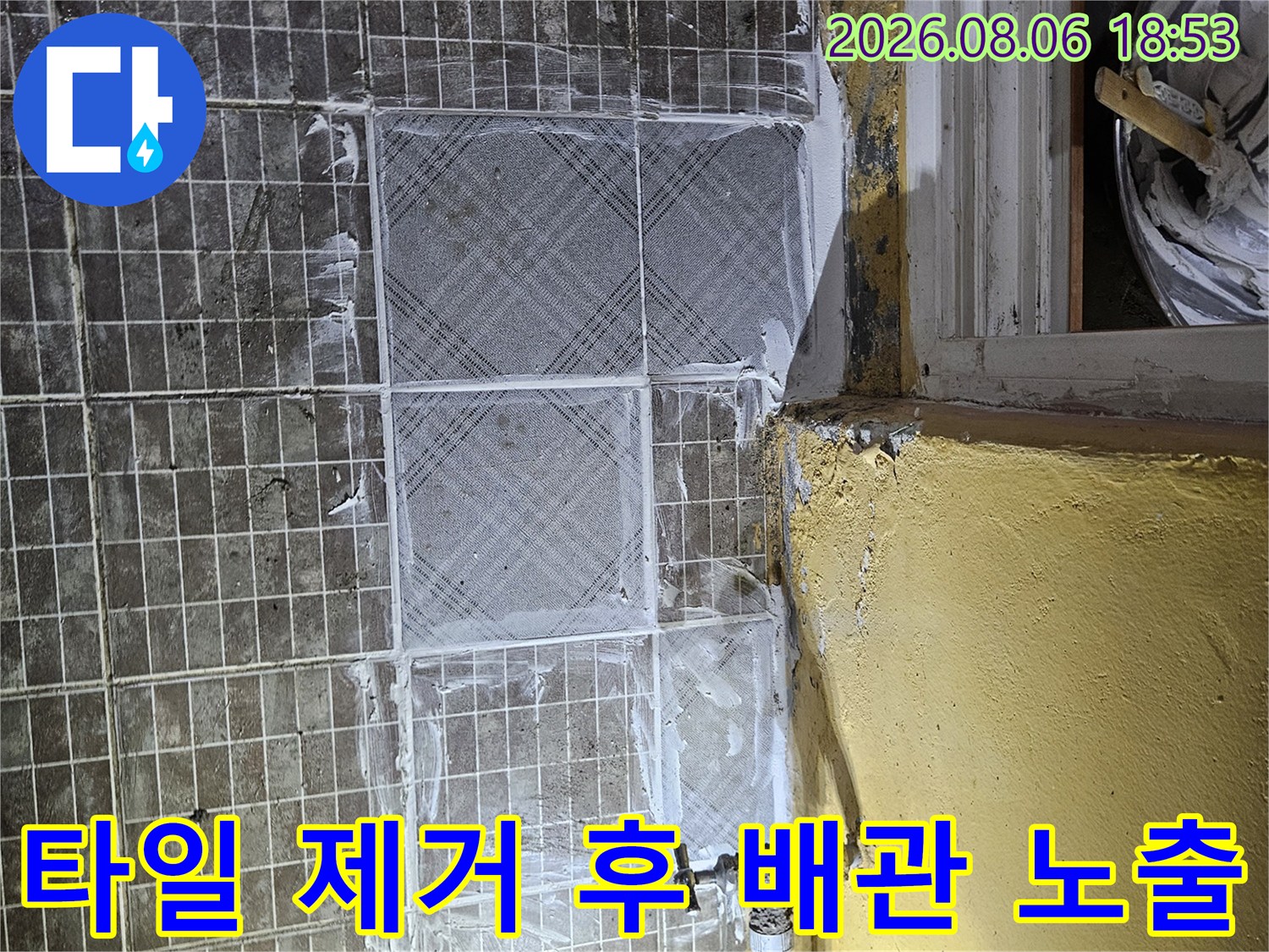 타일을 걷어내고 드러난 보일러 배관과 연결 부위의 상태를 보여줍니다.