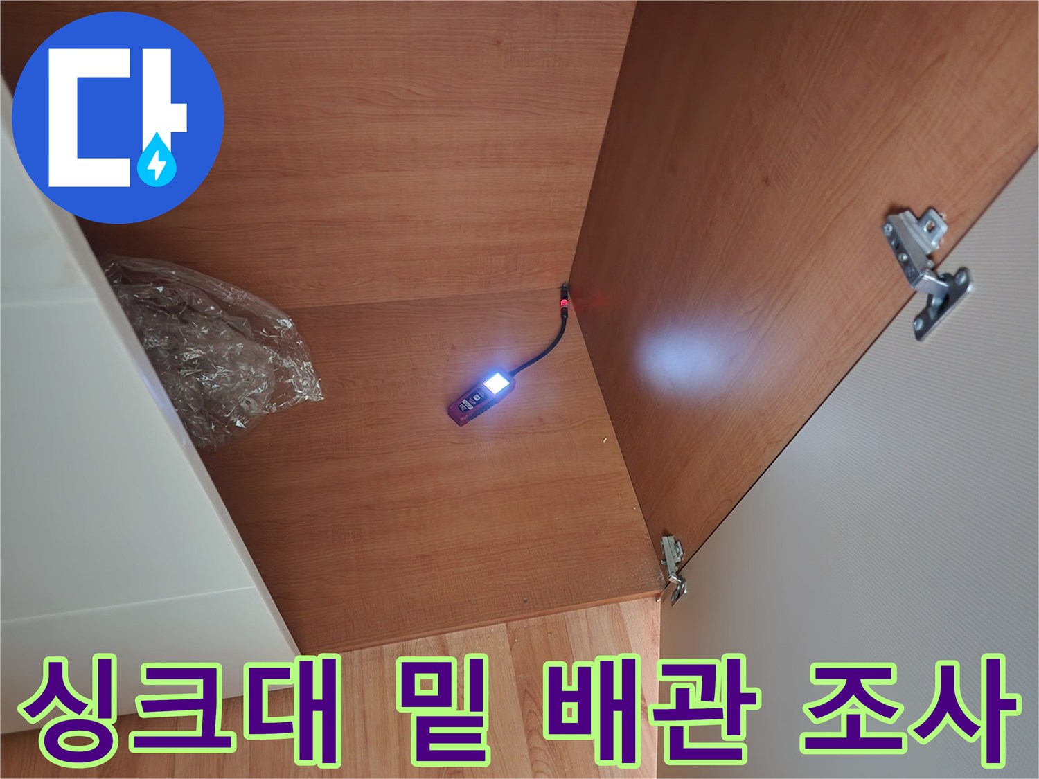 중랑구 면목동 현장의 싱크대 하단 내부를 조명으로 비추어 점검하는 장면
