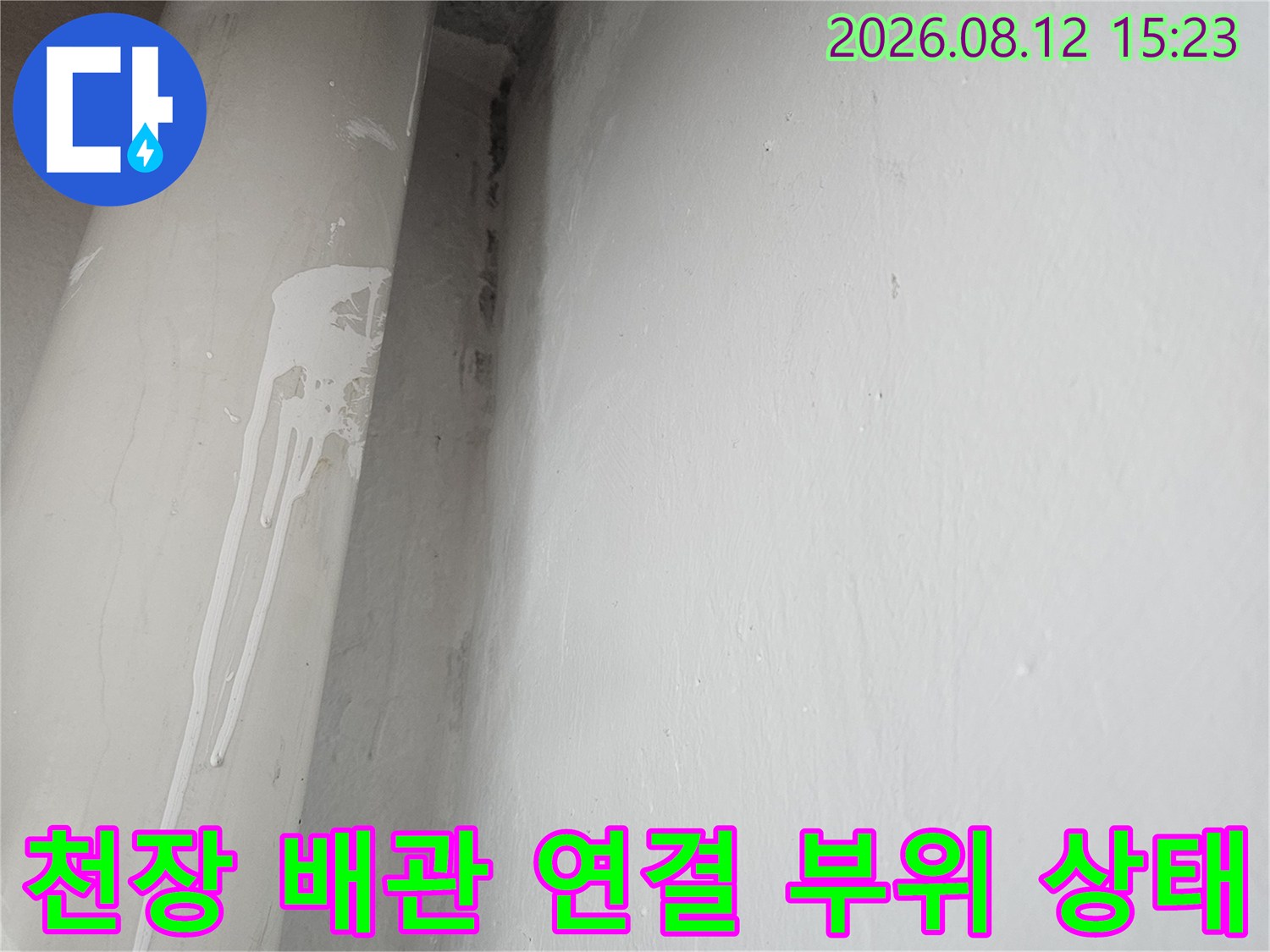 흰색 천장에 설치된 회색 배관의 연결 부위를 근접 촬영한 사진