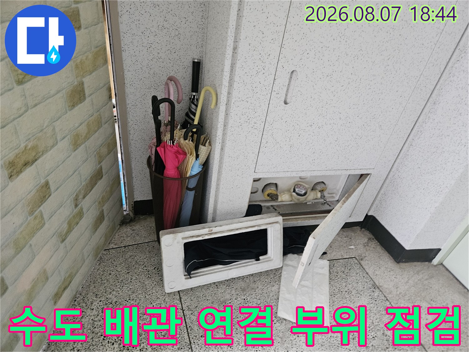 아파트 계량기함 내부에 노출된 수도 배관의 상태를 면밀히 조사하는 모습입니다.