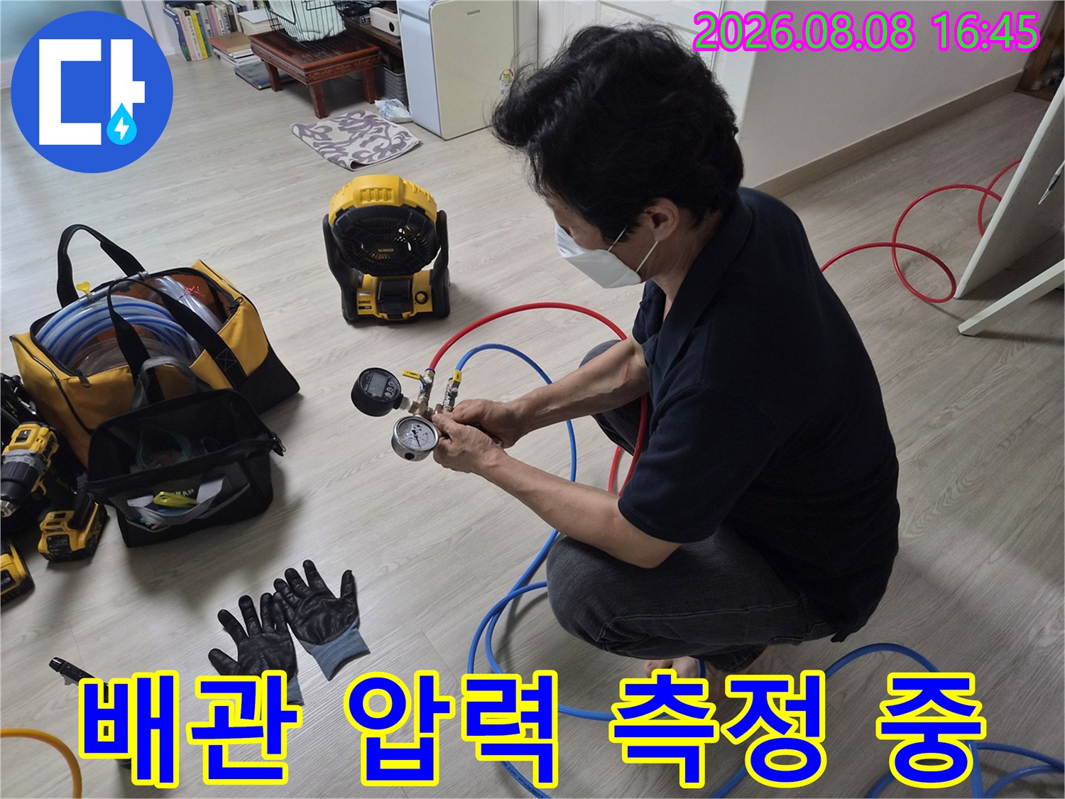 누수 지점을 찾기 위해-공압계와 파란색 호스를 사용하여-압력을 측정하는 엔지니어