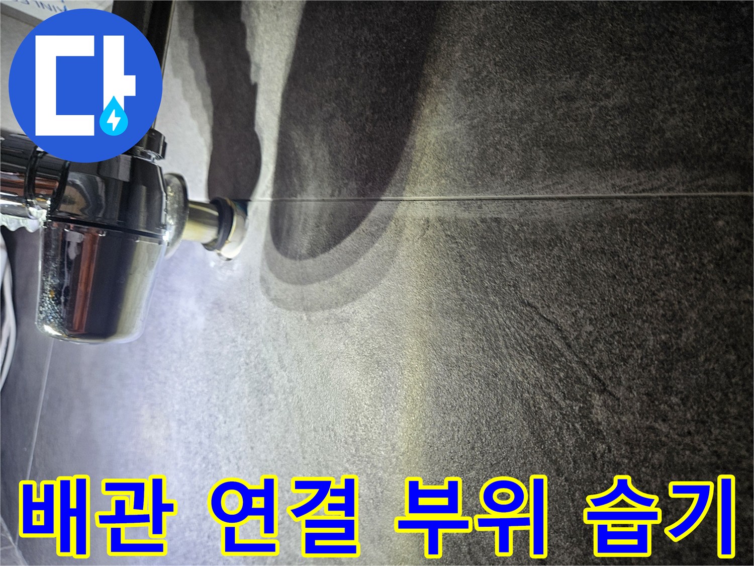 금속 재질의 수도 배관과 어두운 색상 타일의 접촉면
