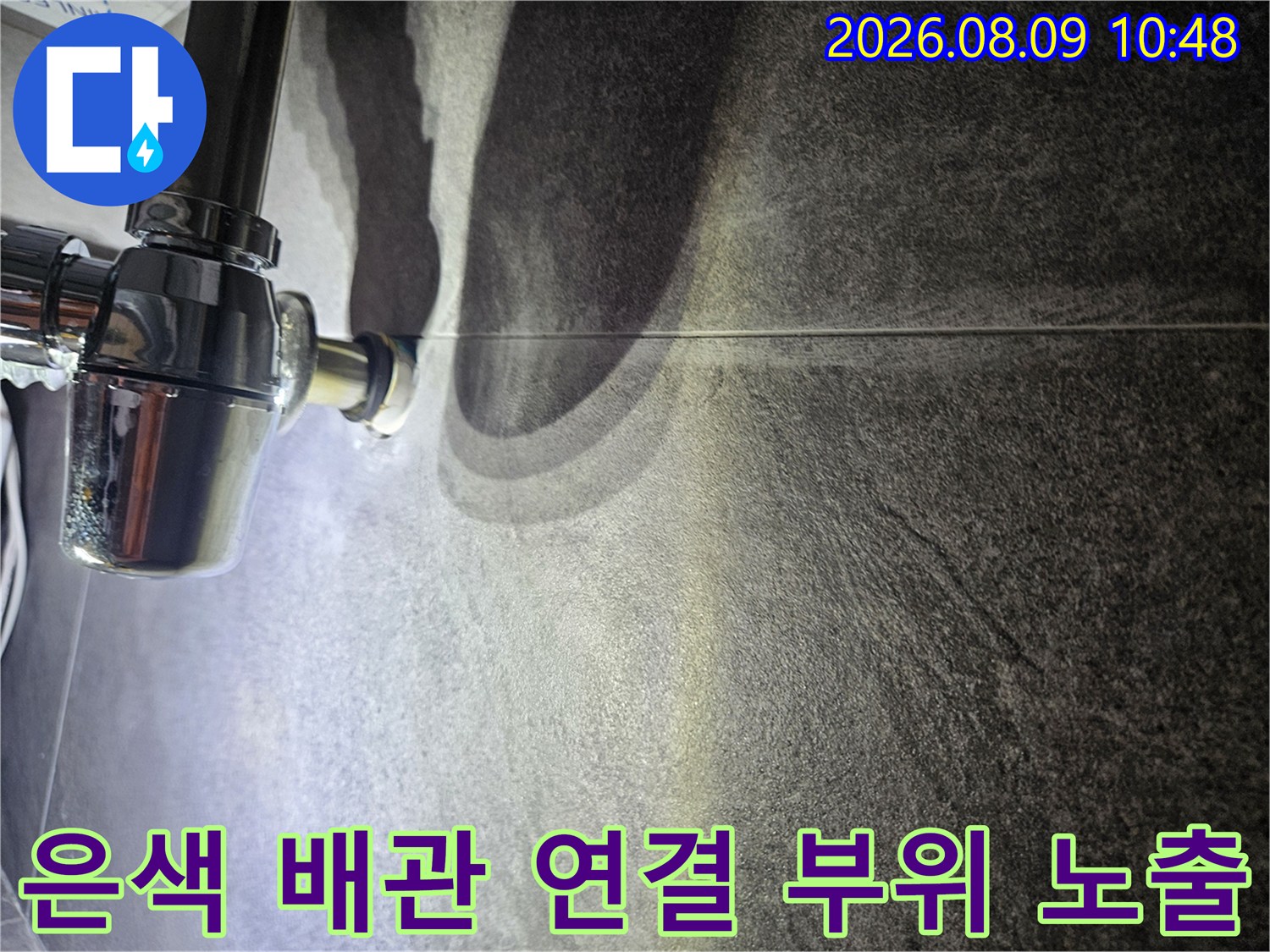 어두운 조명 아래 드러난 은색 금속 재질의 배관 연결부 모습