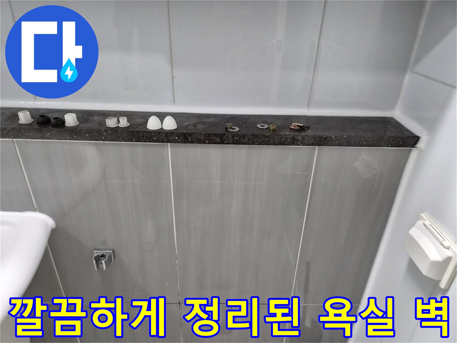 점검 중인 화장실 내부-선반 위 부속들과 정돈된 타일벽