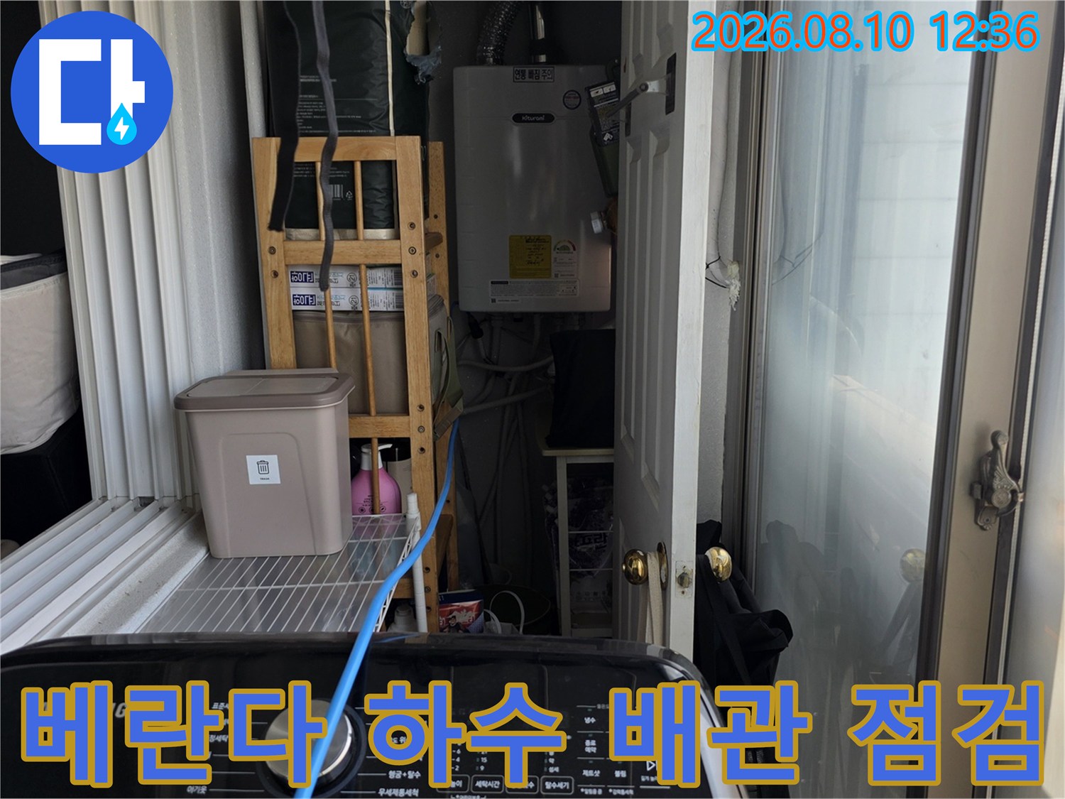 세탁실 베란다 공간의 수도 계량기와 노출된 배관들의 모습입니다.