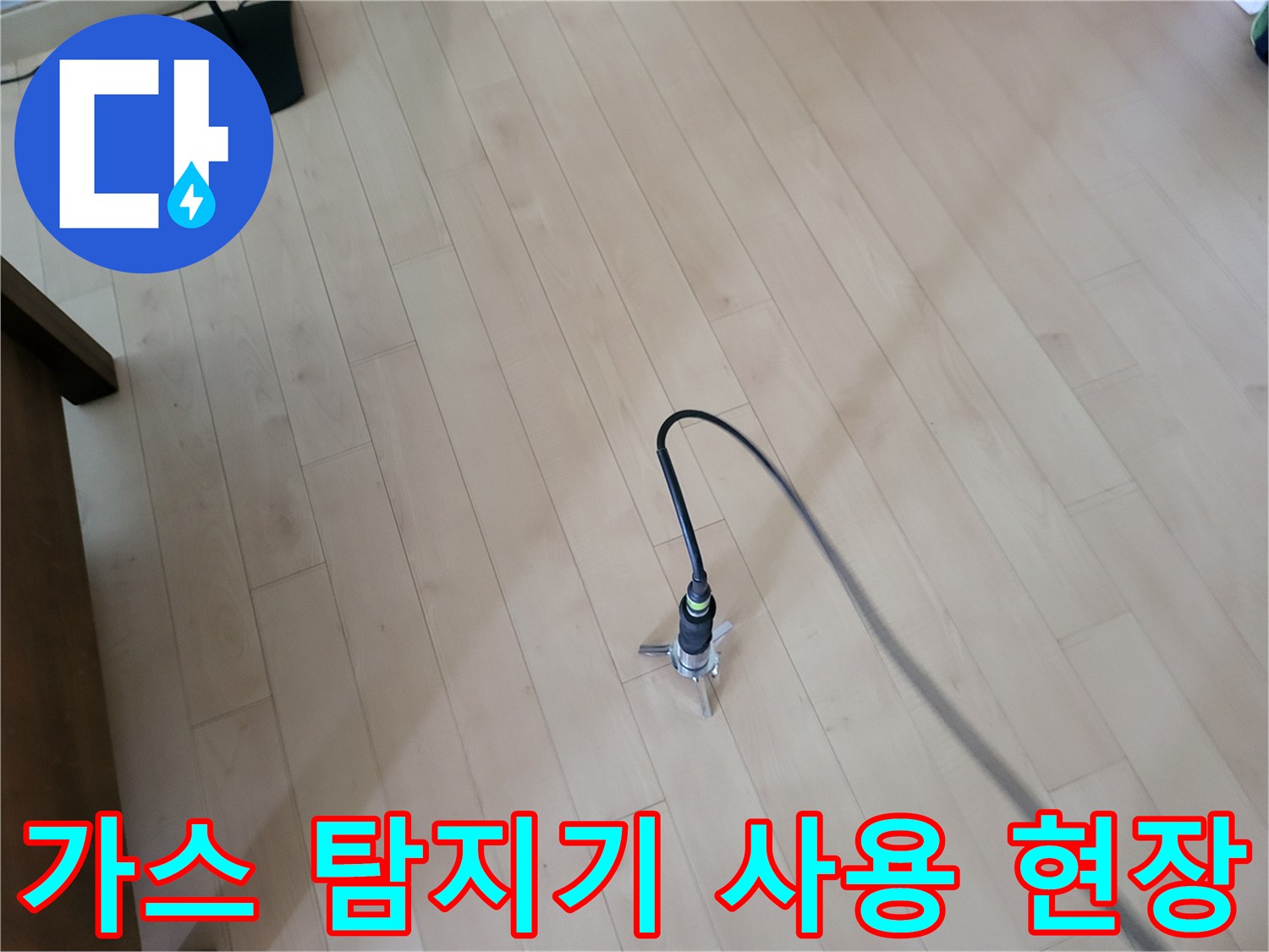 거실 바닥 마루 위에서 가스 탐지기를 활용하여 배관 누수 지점을 정밀하게 찾는 모습입니다.