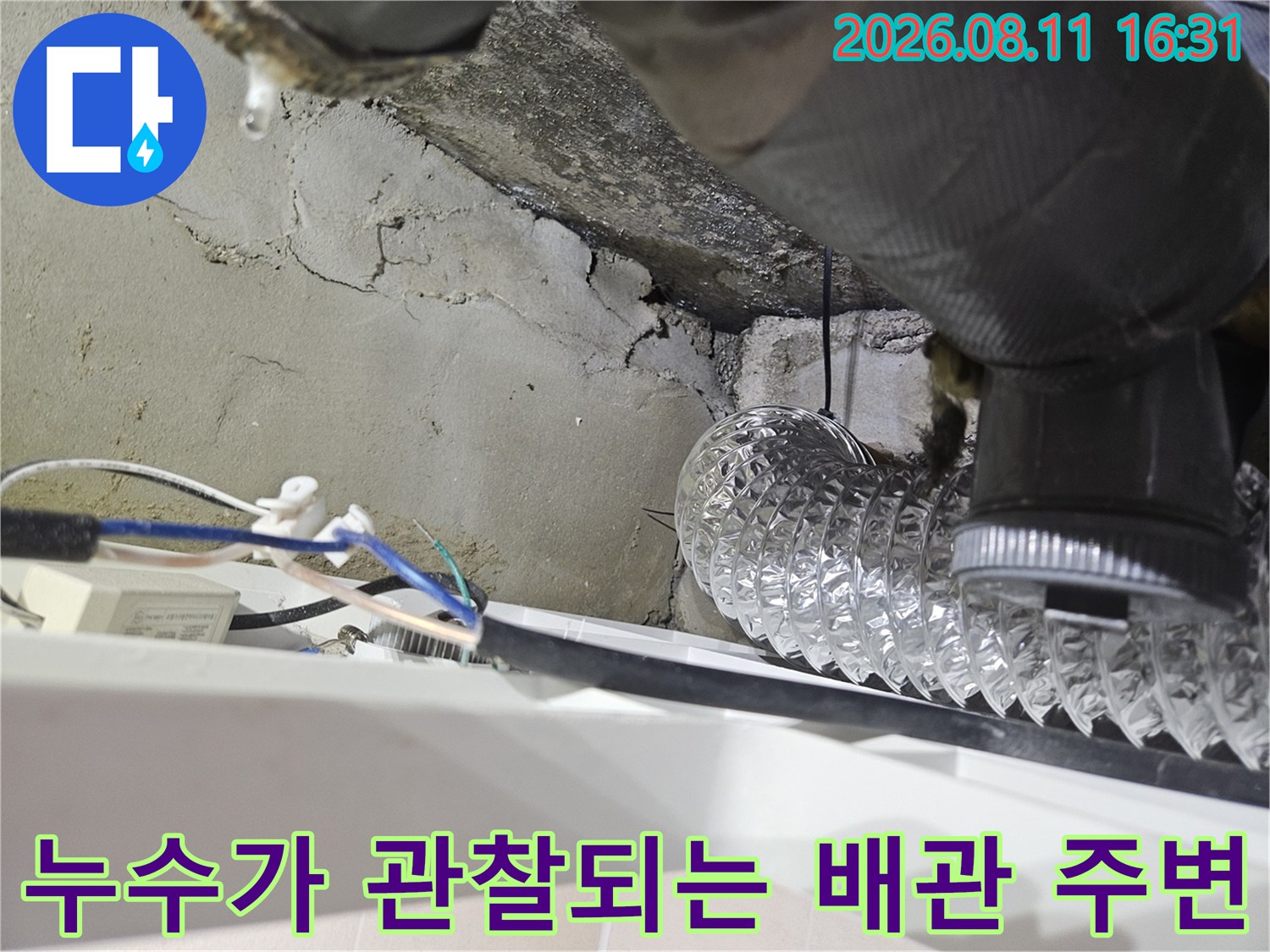 천장 내부 은색 배관과 물기에 젖은 콘크리트 벽면의 접촉 부위