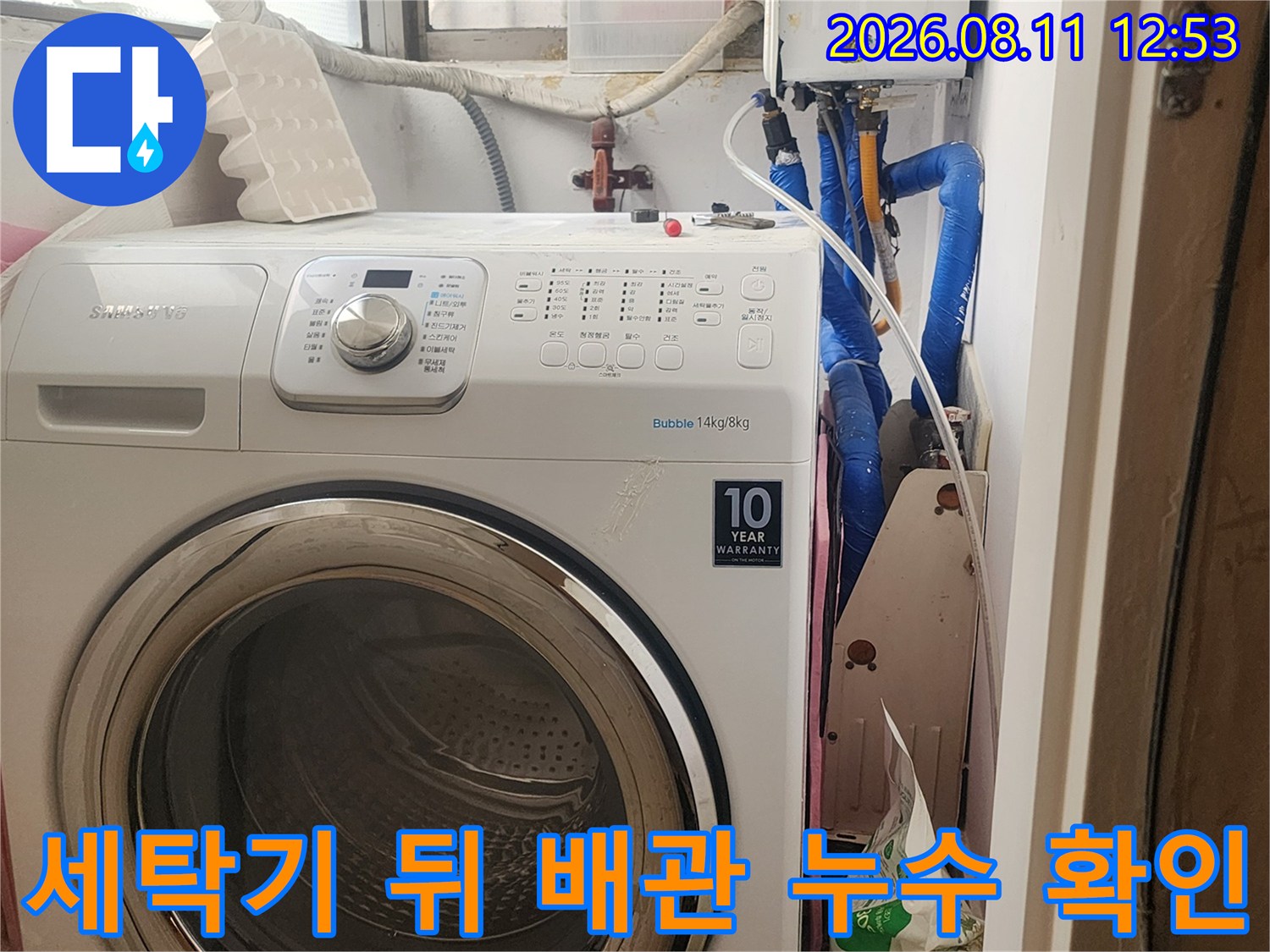 파란색 수도 배관과 보일러 제어 장치가 보이는 세탁실 내부의 모습입니다.