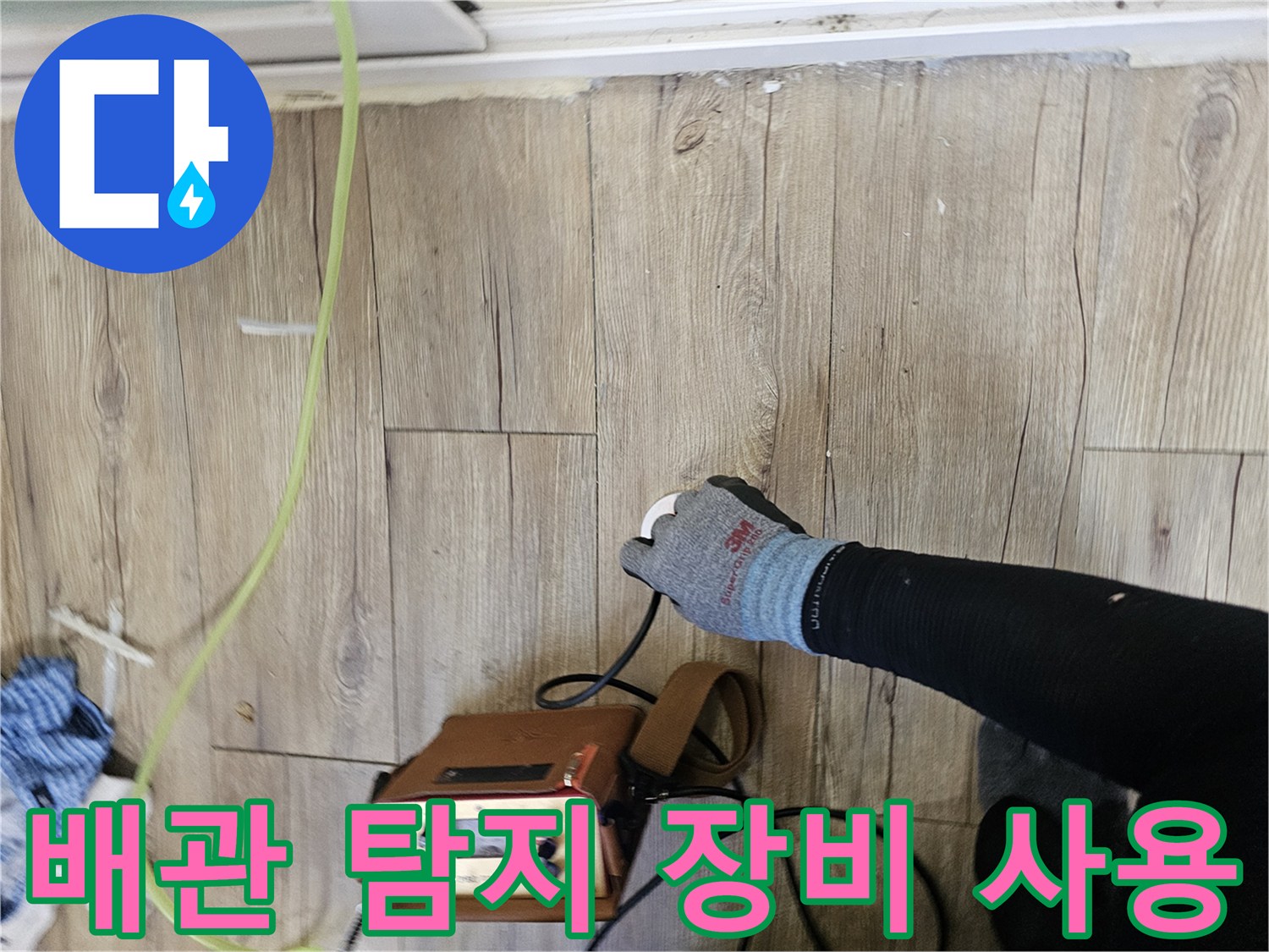 나무 바닥재 위에서-배관 누수를 확인하기 위해-정밀 탐지기를 사용하는 모습