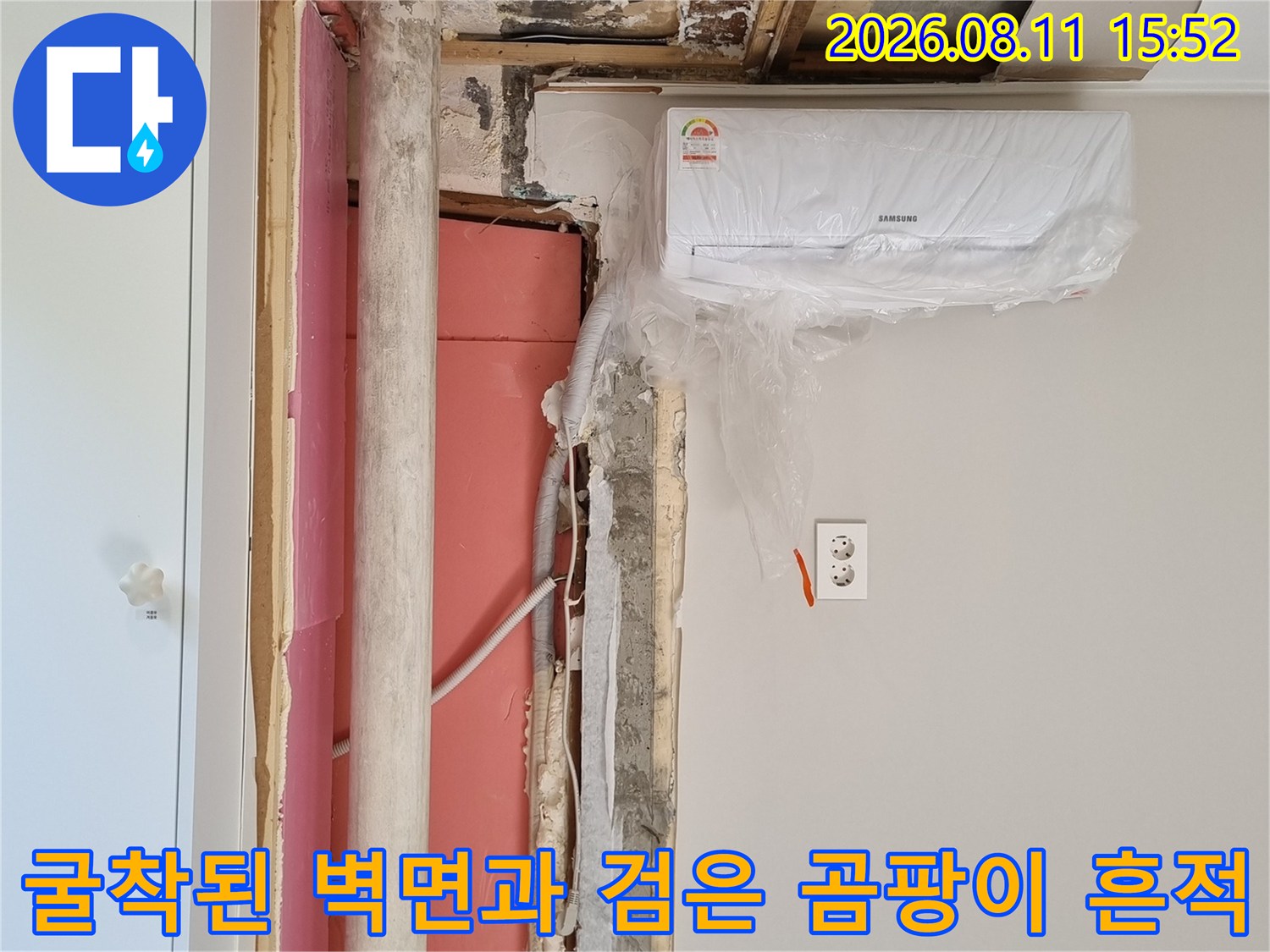 벽지가 제거되고 시멘트 벽면에 검은색 곰팡이가 핀 상태에서 내부 배관이 노출된 모습