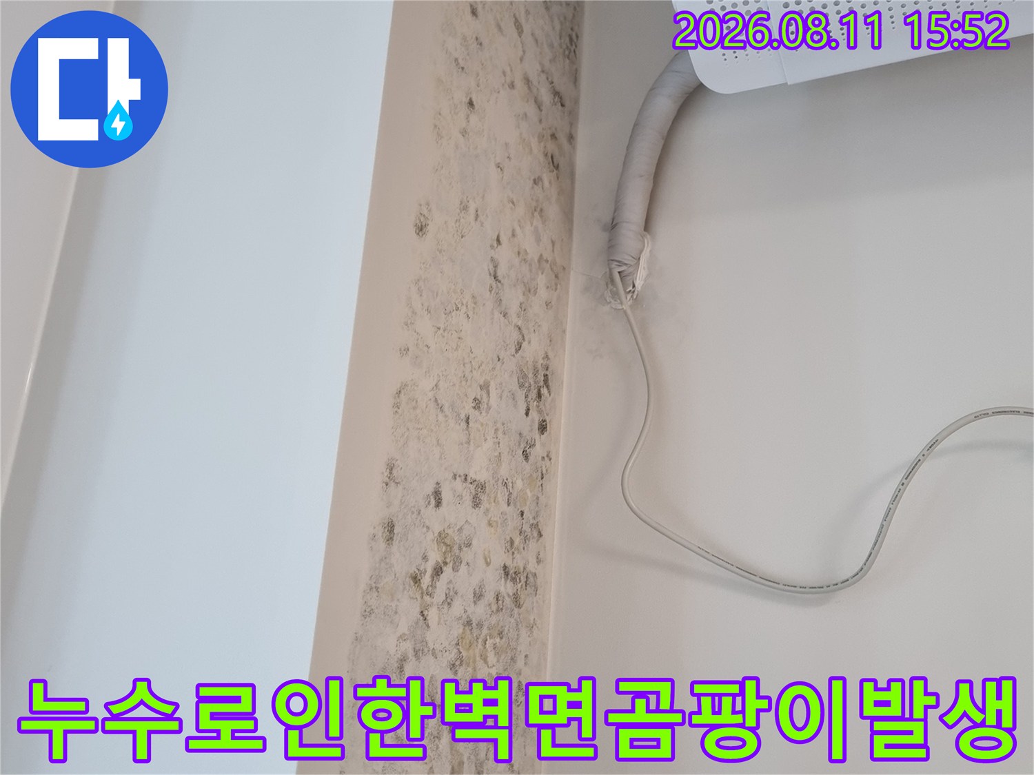 에어컨 실내기 아래쪽으로 연결된 회색 호스와 오염된 흰색 벽면의 상세 사진