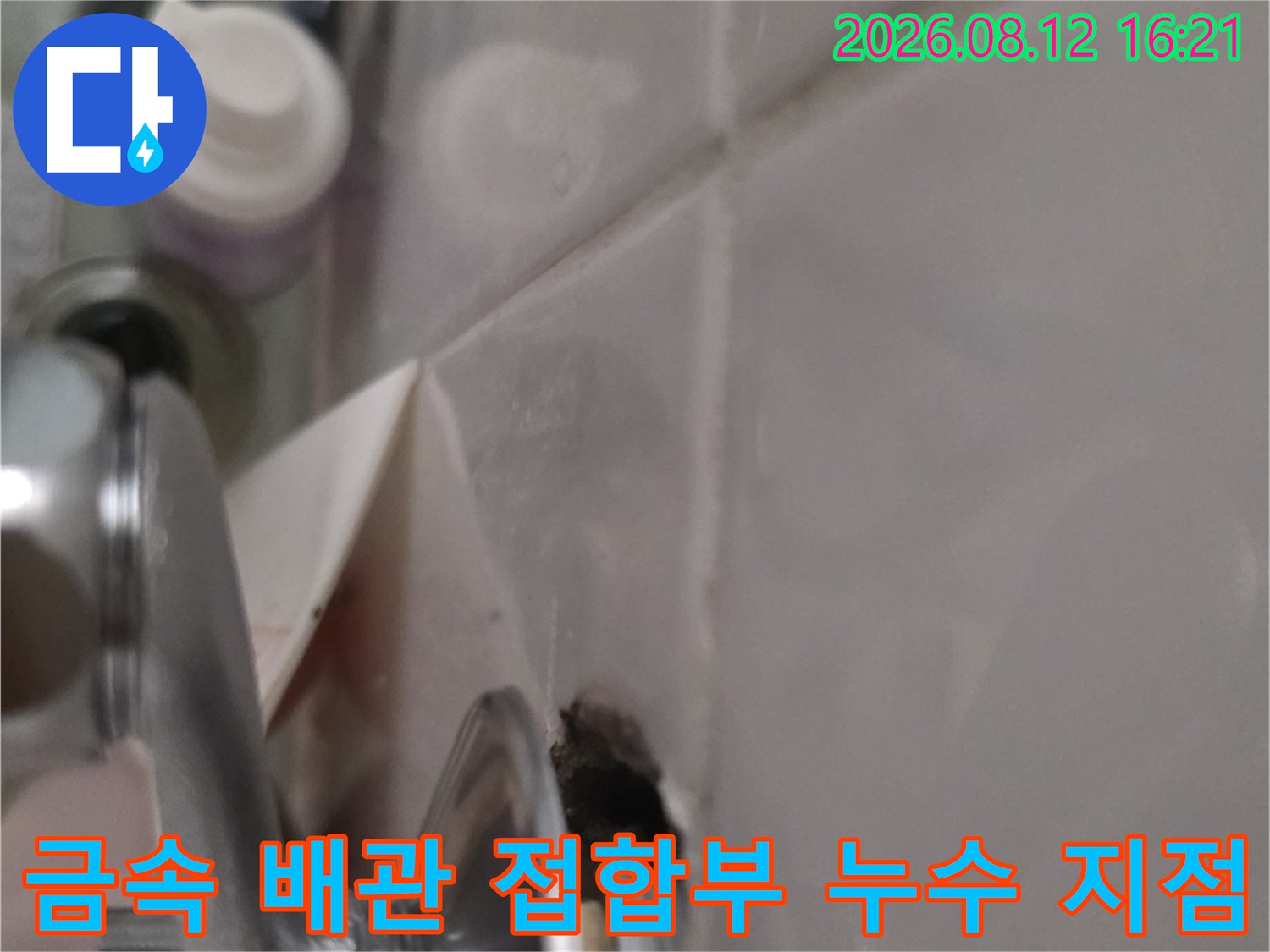 세면대 하부의 크롬 도금 배관과 천장 타일 사이의 틈새 모습
