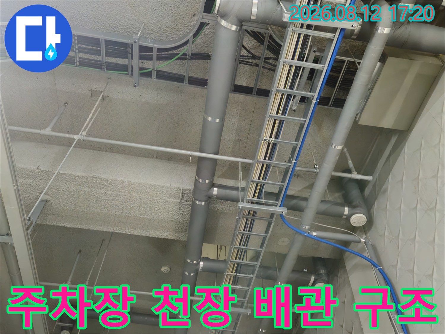 지하 주차장 천장에 설치된 회색 PVC 배관과 전기 트레이 라인