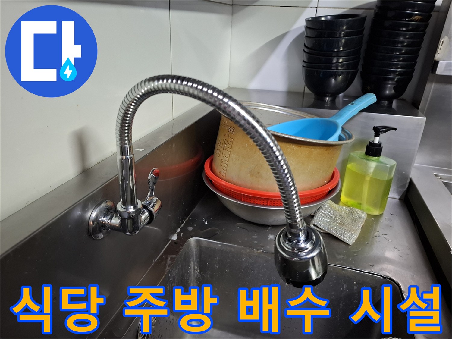 싱크대 하부의 스테인리스 배수 트렌치와 주방 집기류 모습