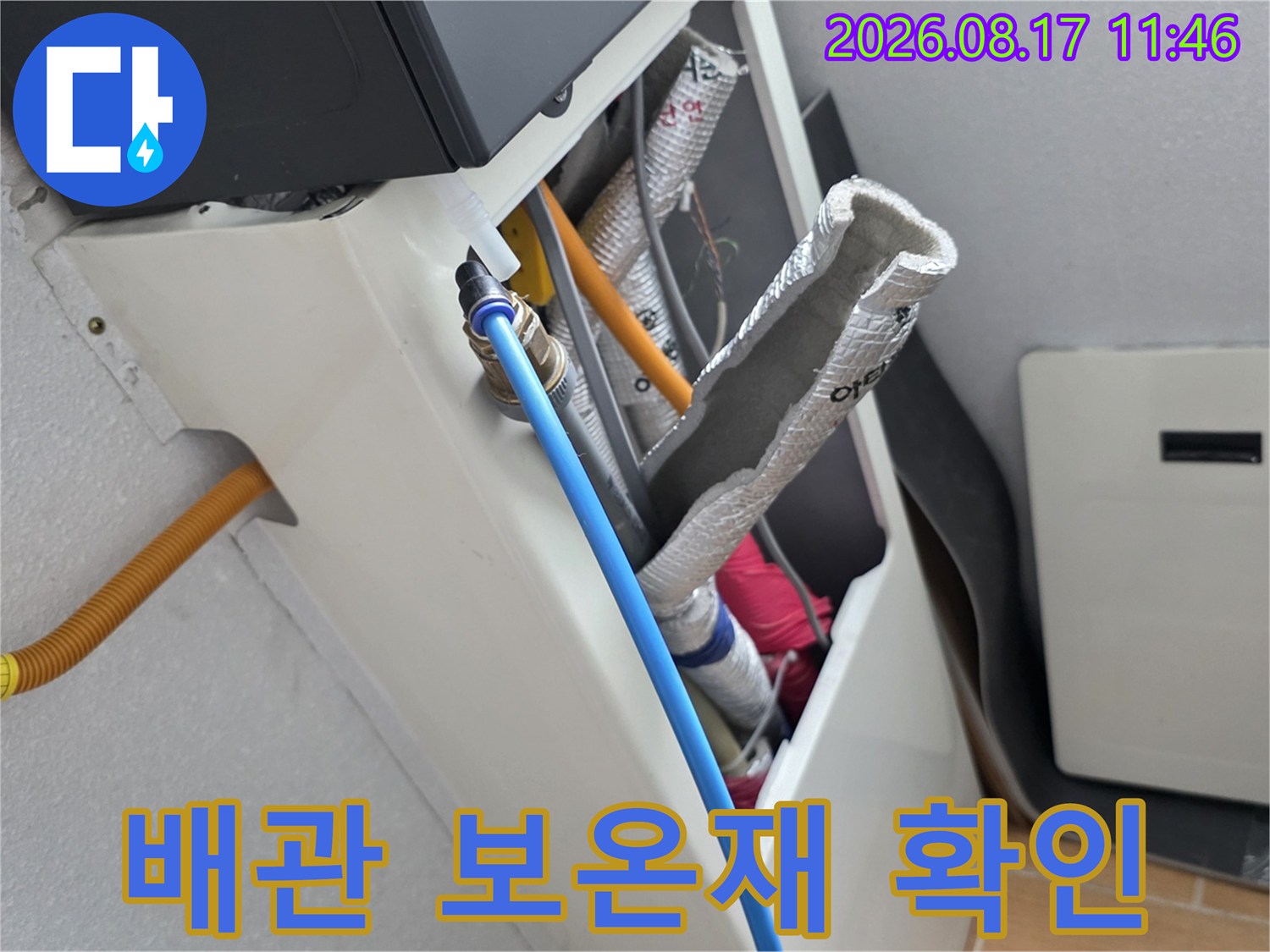 은박 보온재로 감싸진 배관과 파란색 호스가 연결된 모습