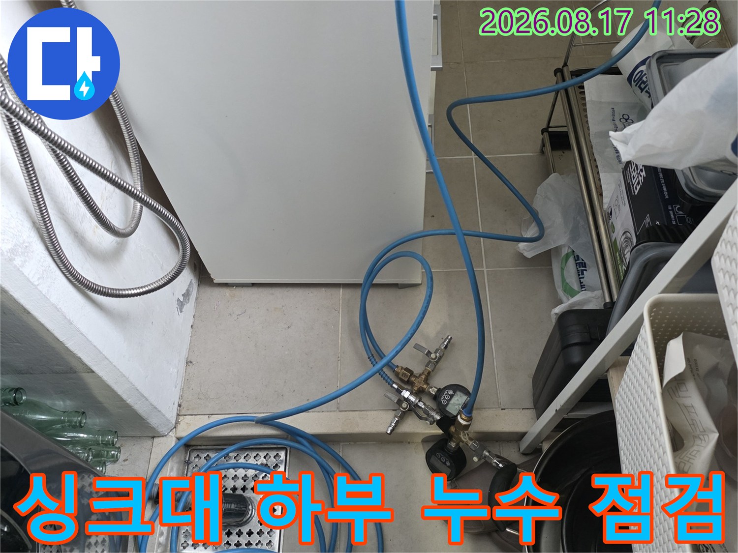 싱크대 하부 배관 주변에 공압 검사용 호스가 연결되어 있는 모습