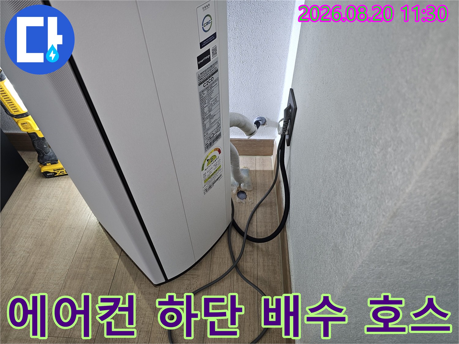 에어컨 본체 아래쪽에서 벽면으로 연결된 흰색 드레인 배관 모습