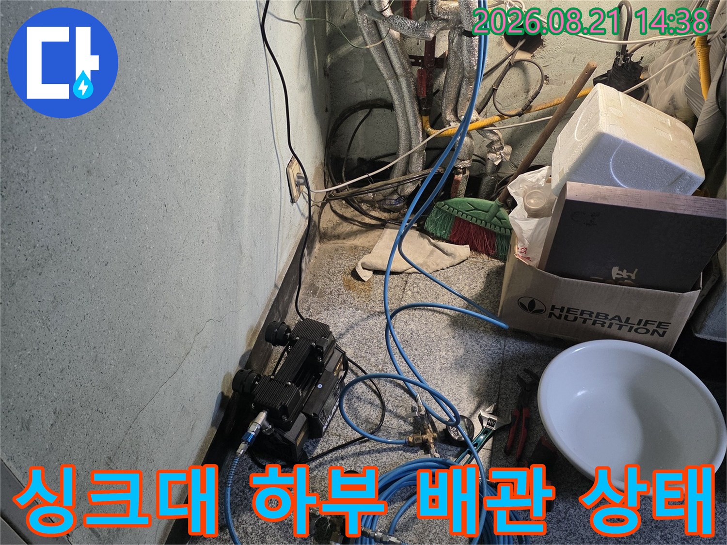싱크대 아래 복잡한 배관 구조와 점검을 위한 장비가 배치되어 있습니다.